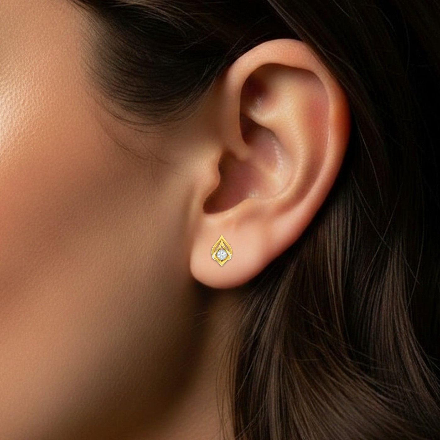 Close-up of an ear wearing a gold and diamond stud earring.