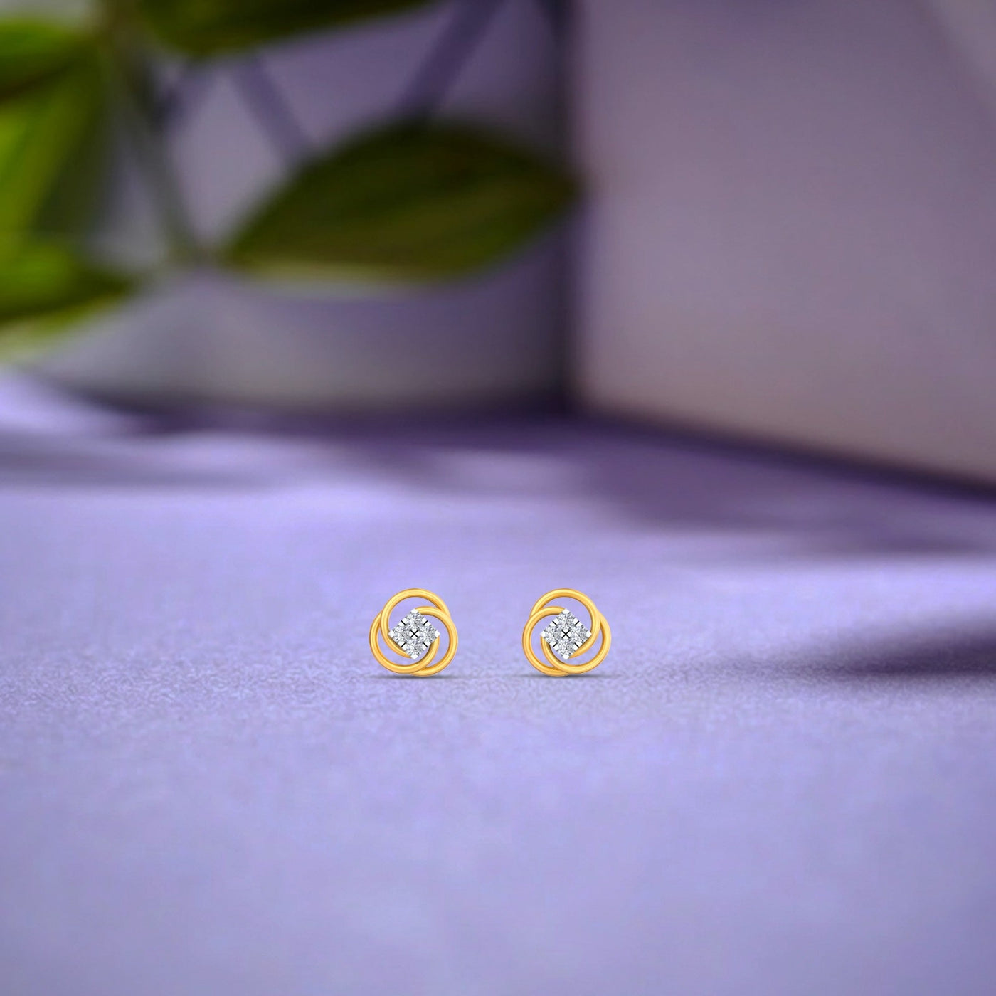 Gold and diamond floral stud earring on a purple surface.