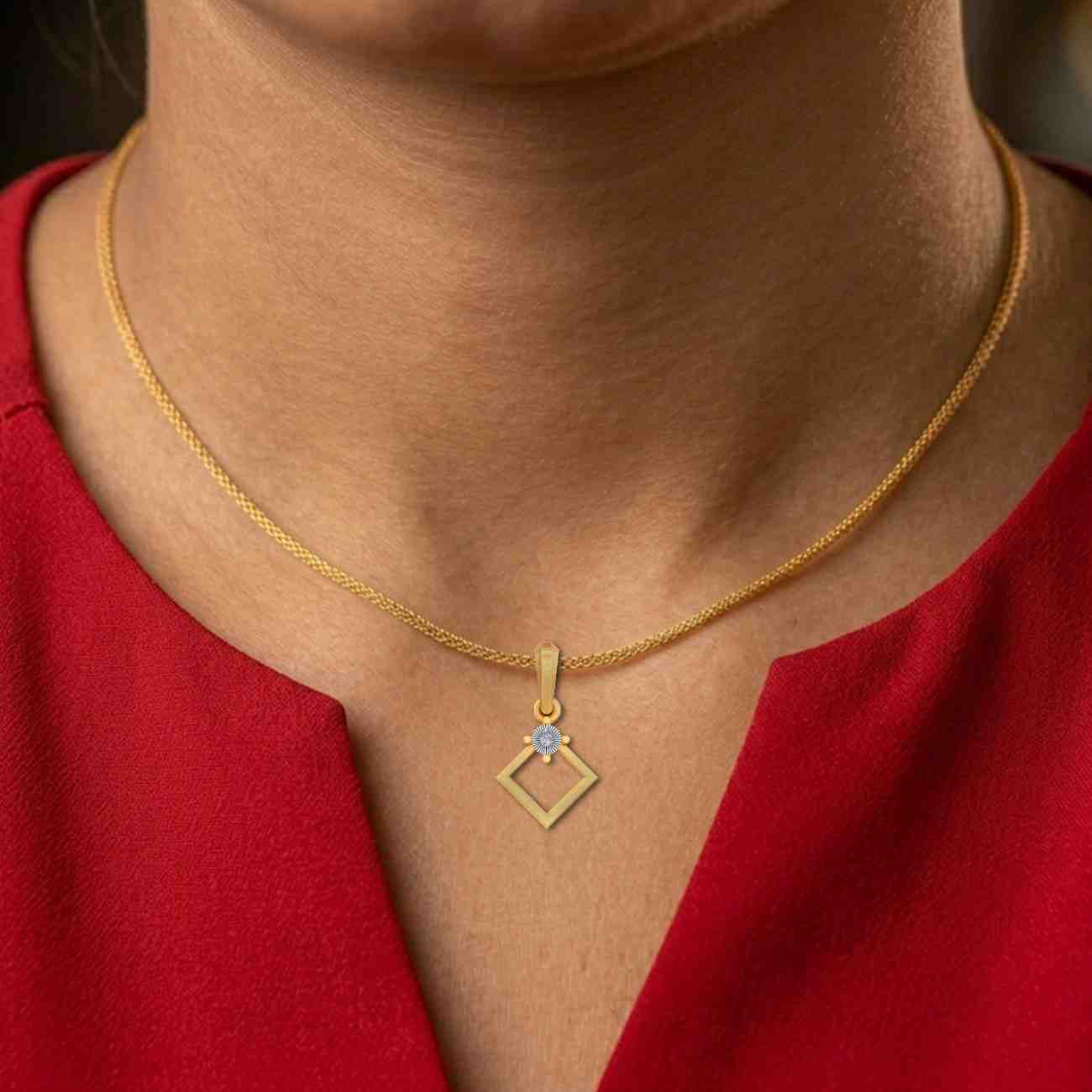 Gold necklace with a diamond-shaped pendant worn by a person in a red top.
