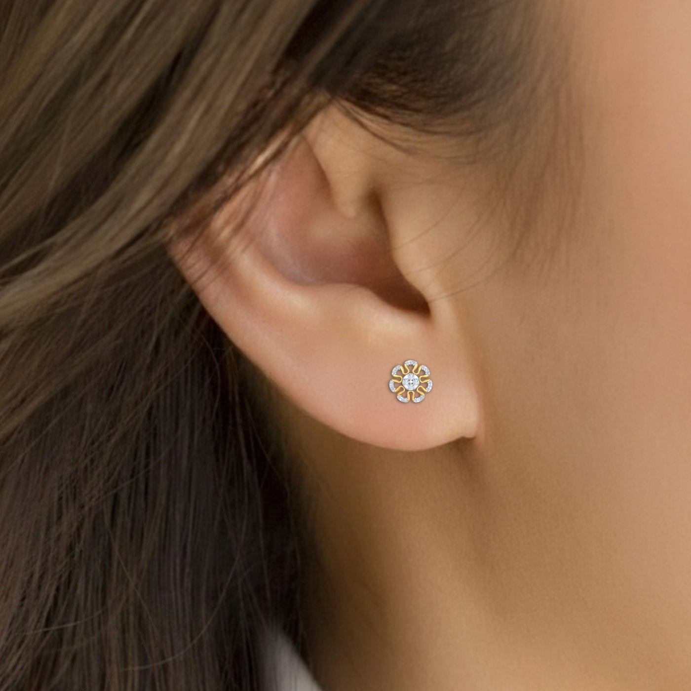 Close-up shot of a gold and diamond stud earring with floral-design.