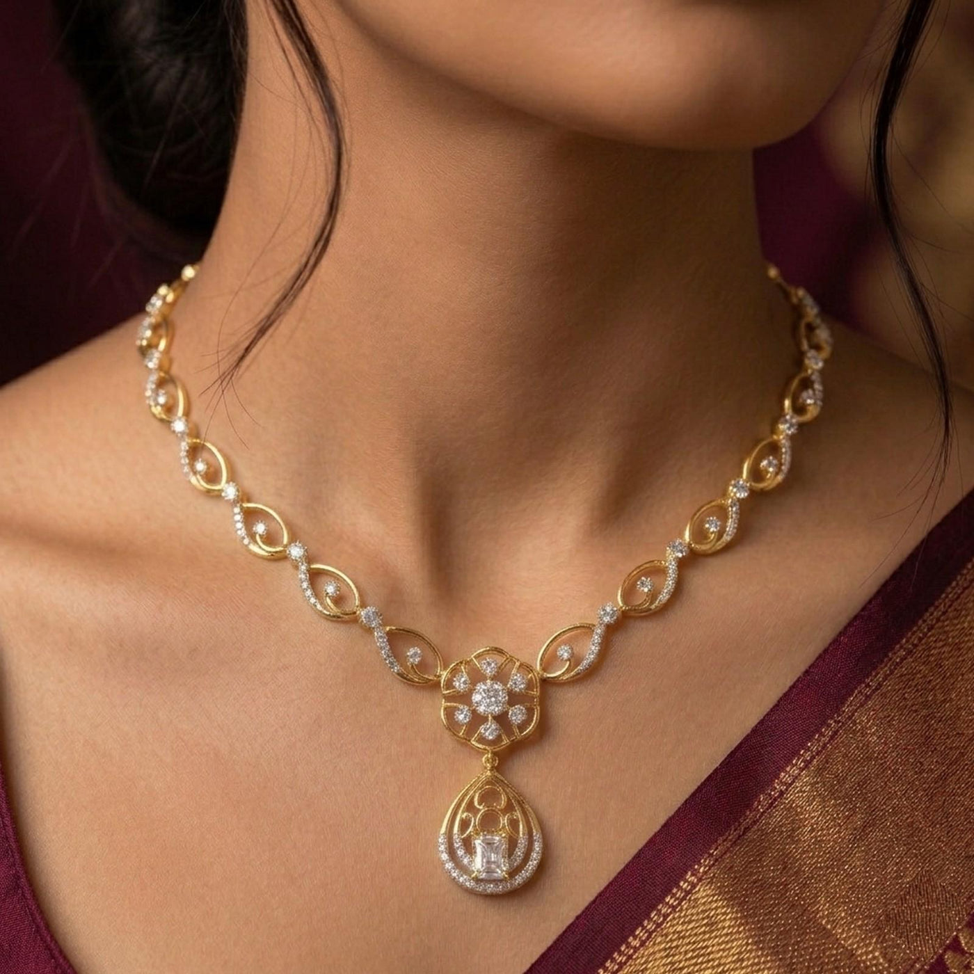 Gold necklace with a diamond on a person wearing a brown saree.
