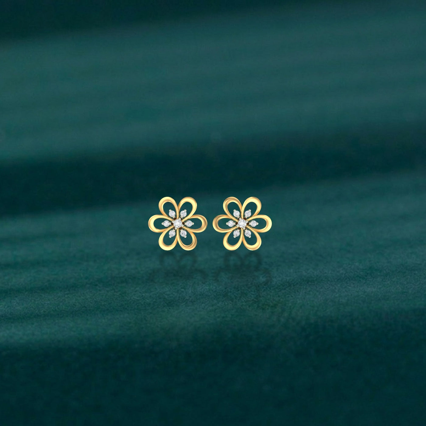 Gold and diamond stud earring with floral-design on a teal background.