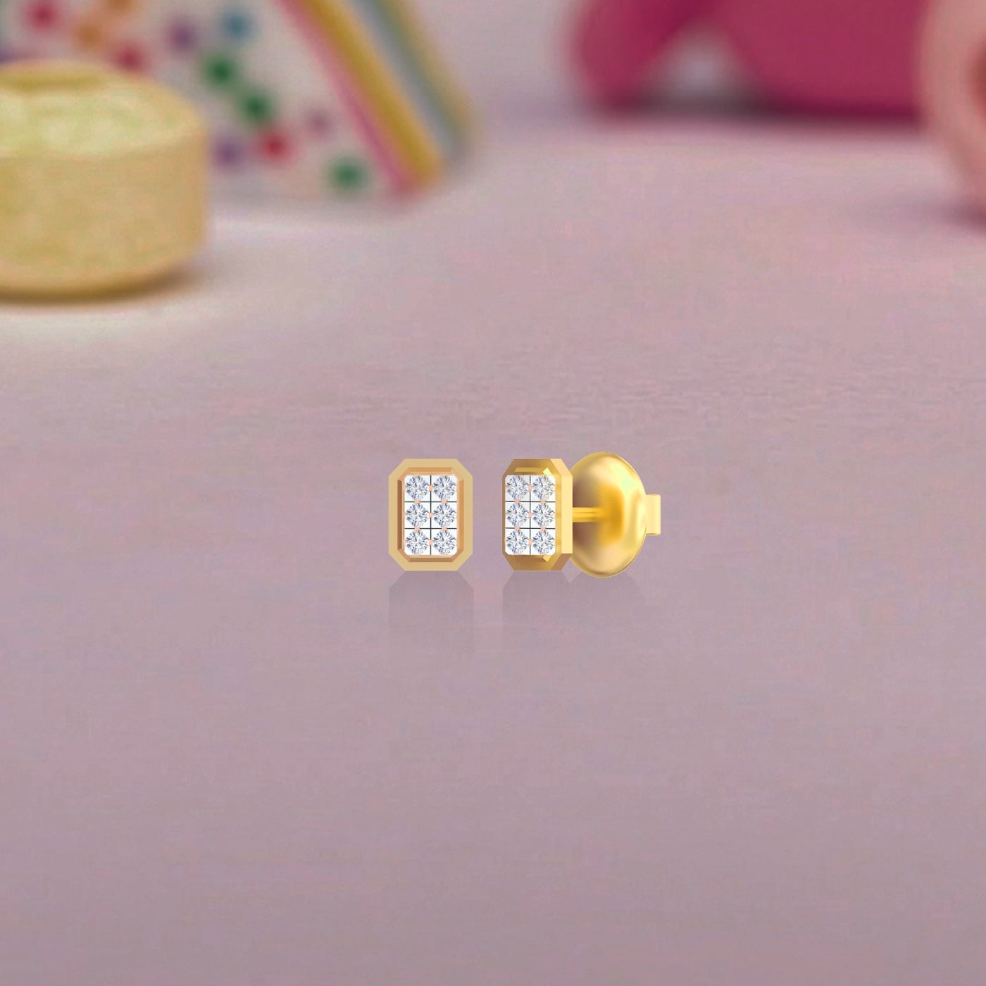 Gold and diamond square stud earrings on a pink surface