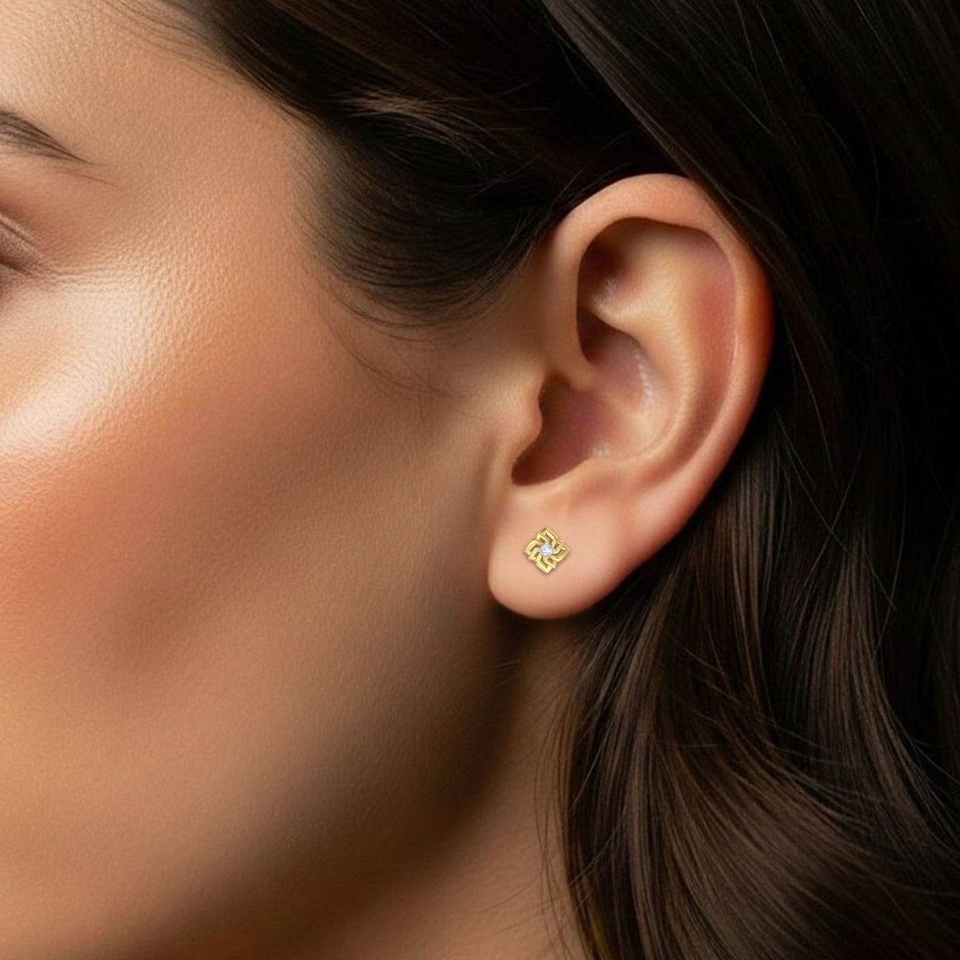 Close-up of an ear wearing a gold and diamond swirl stud earring.