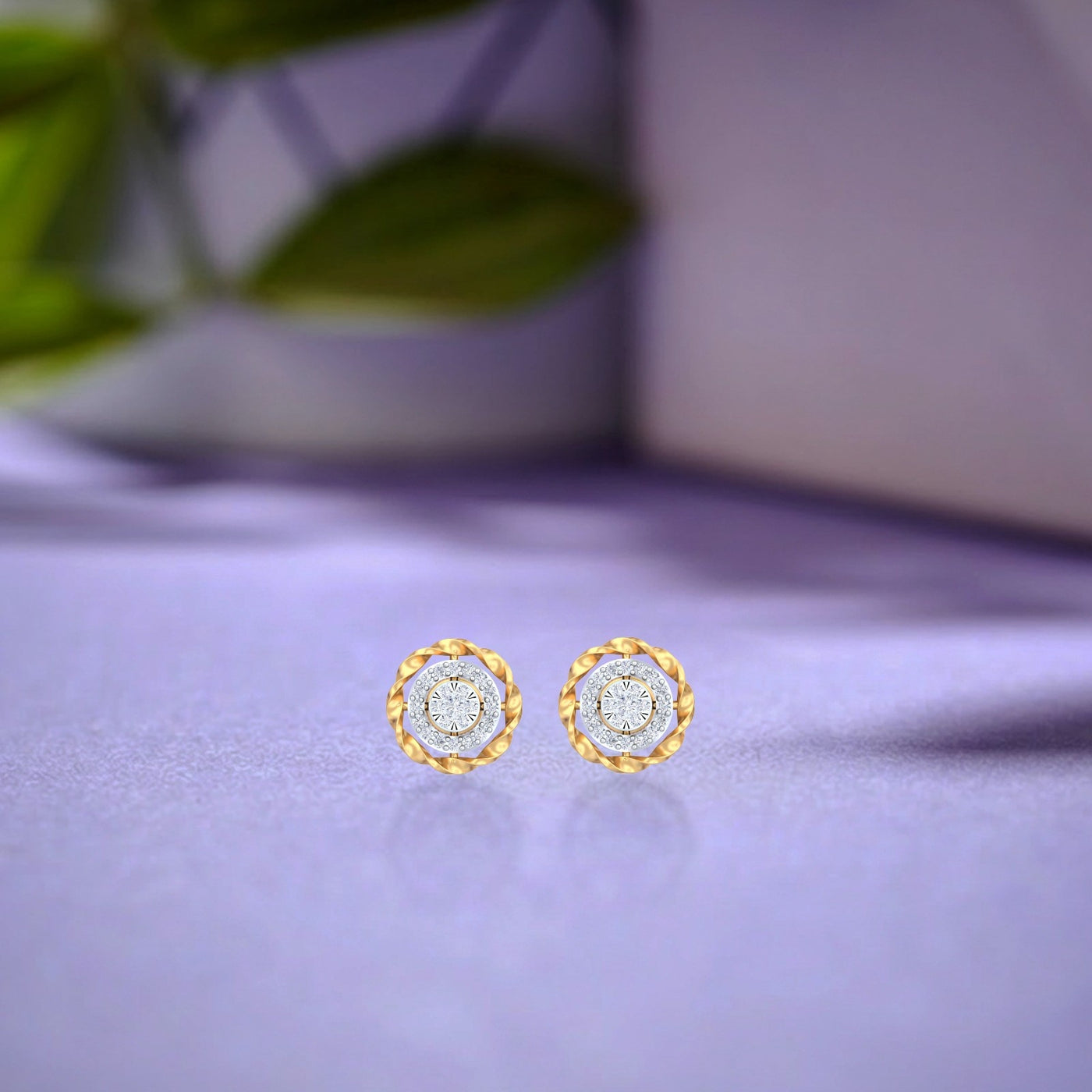 Pair of gold and diamond halo-shaped stud earrings on a reflective surface. 