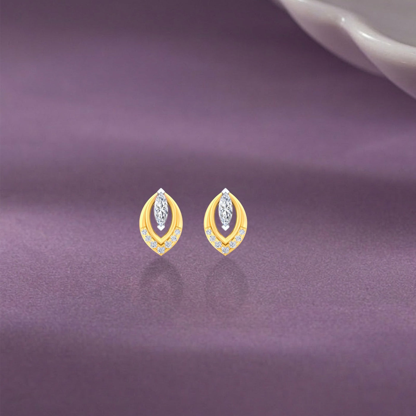 Gold and diamond stud earrings with marquise-design on a purple background