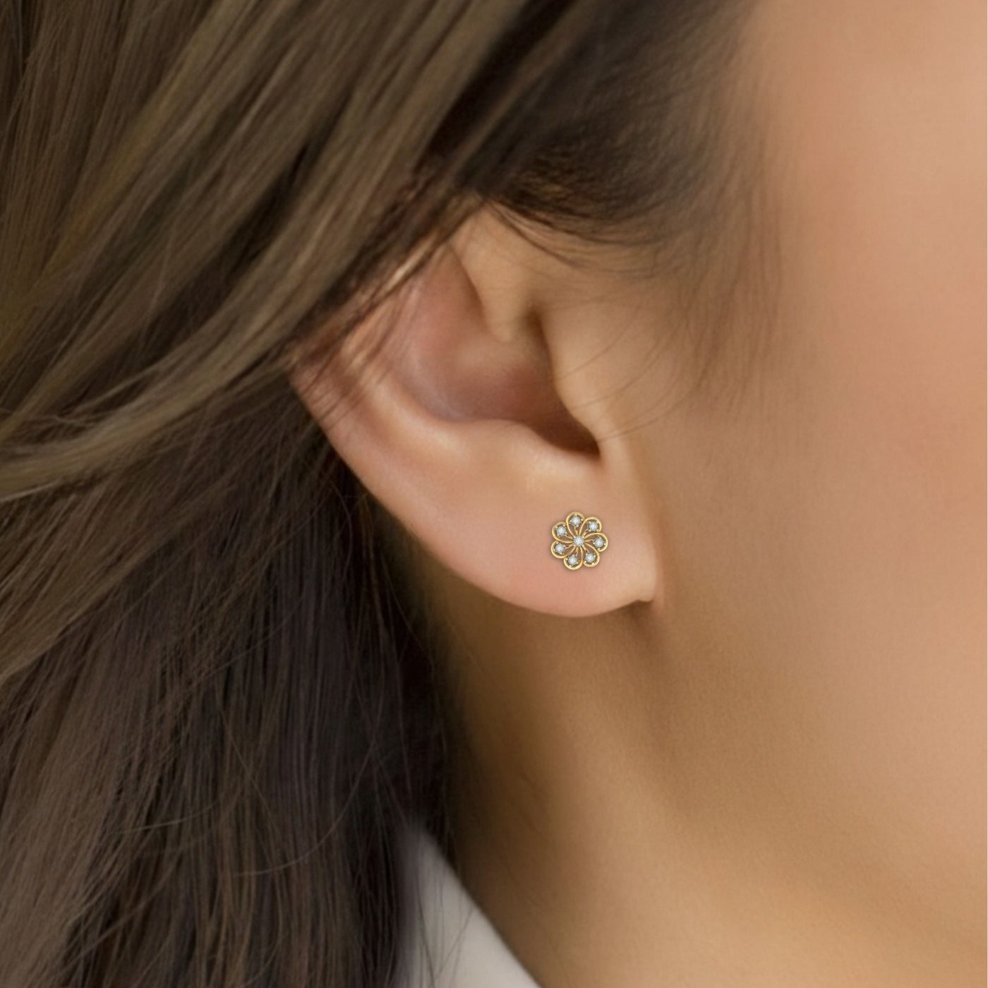 Close-up shot of a gold and diamond stud earring with floral-shaped.