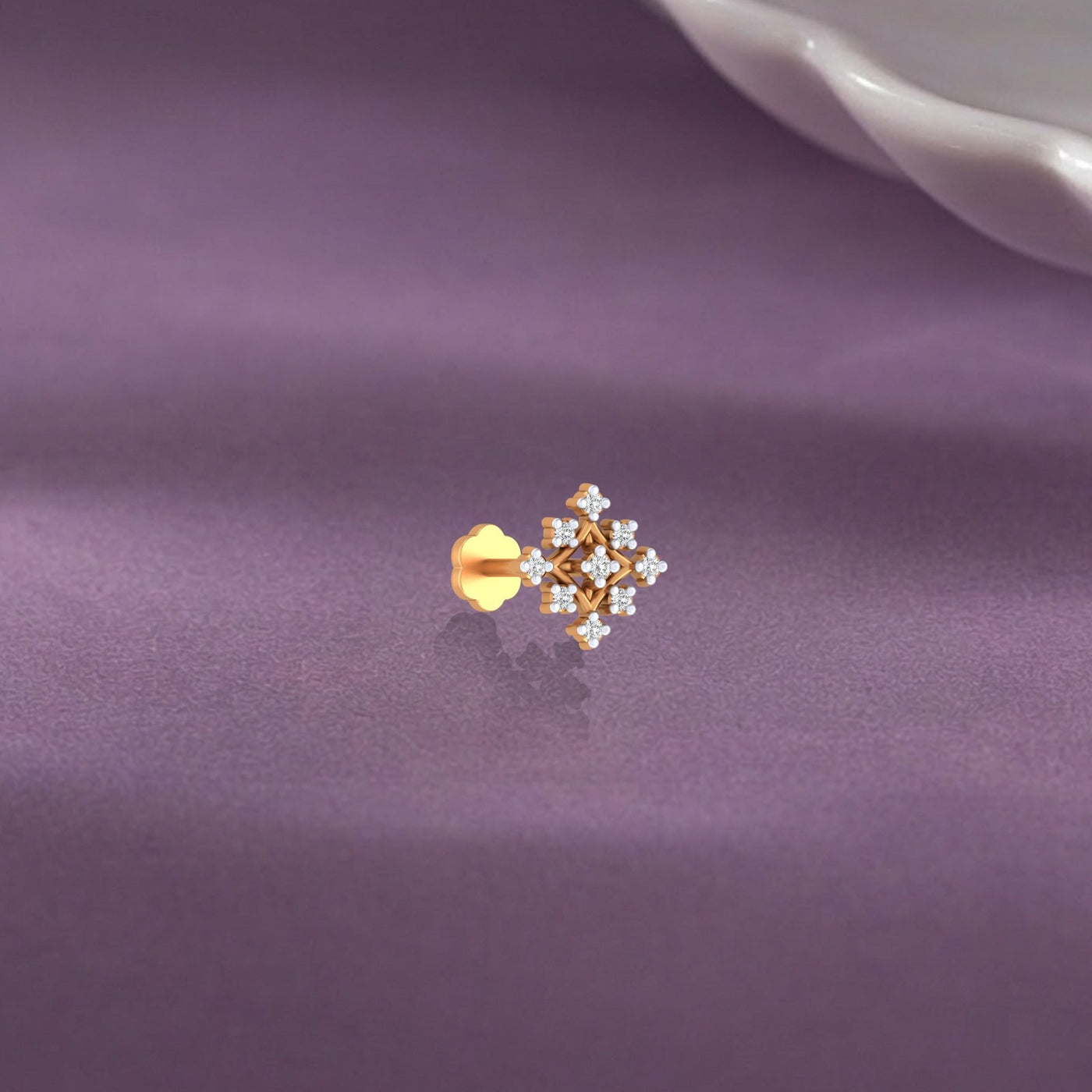 Yellow Gold and diamond stud nose pin on a purple fabric background