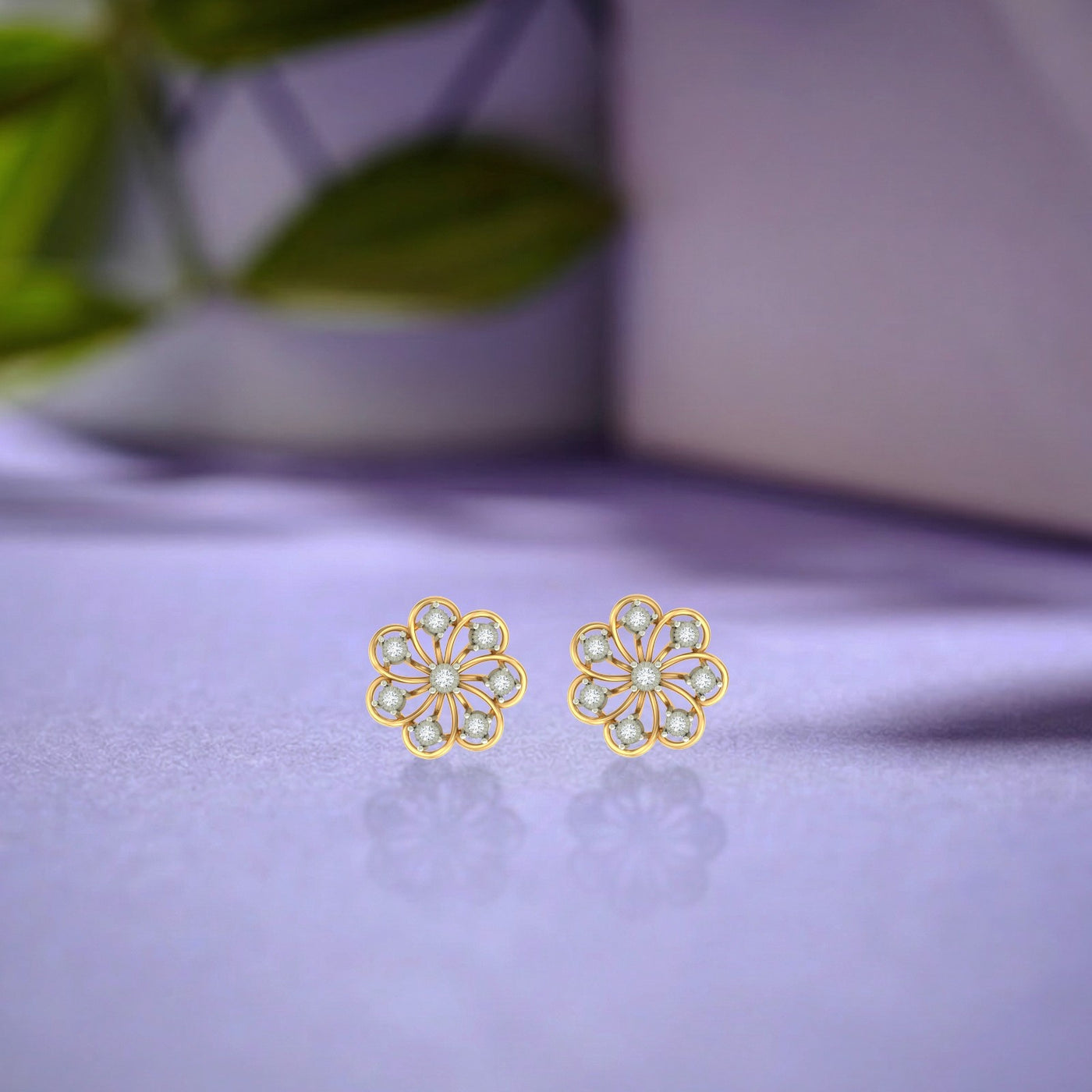 Gold and diamond stud earring with floral-shaped on a blue surface.