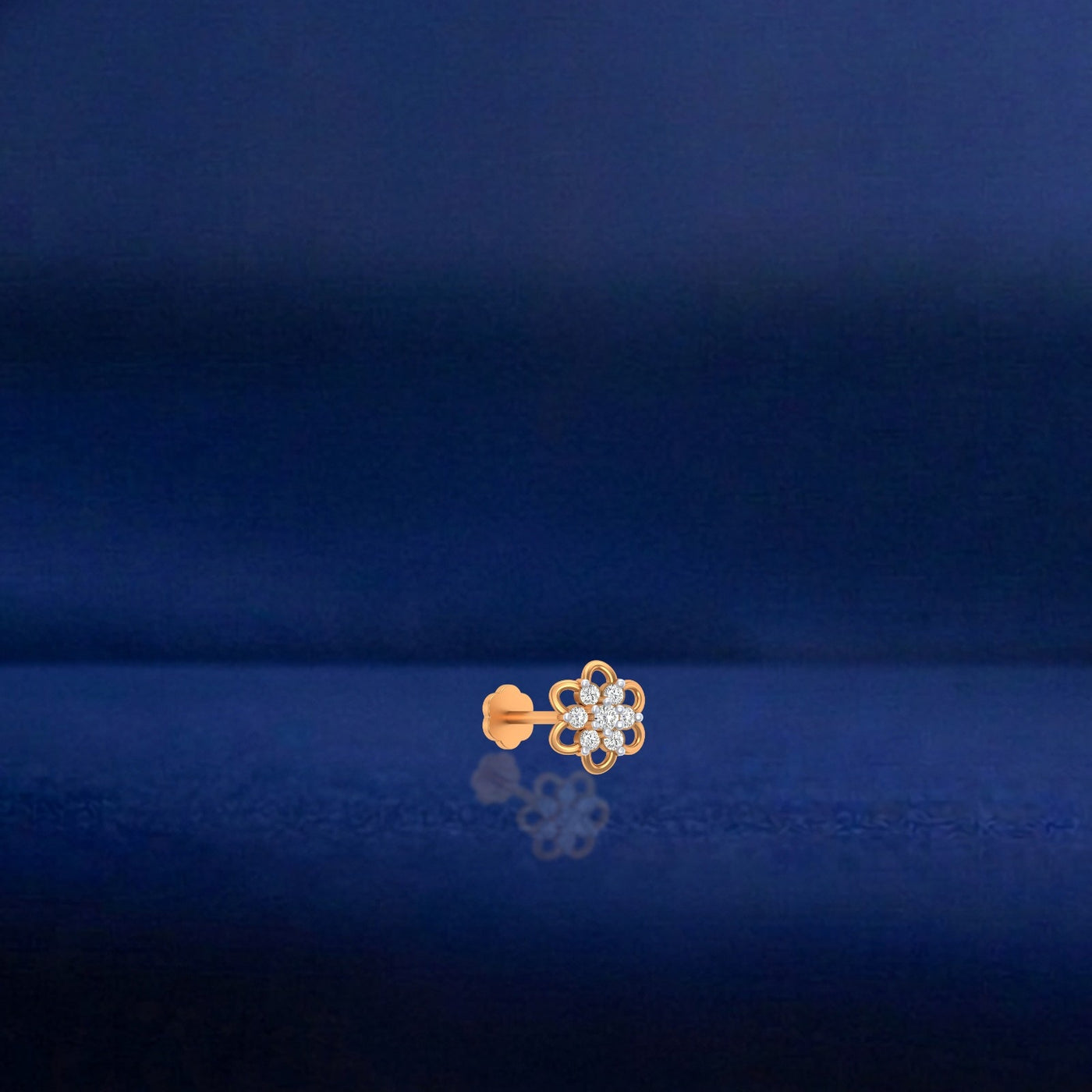 Yellow Gold and diamond stud nose pin on a dark blue background