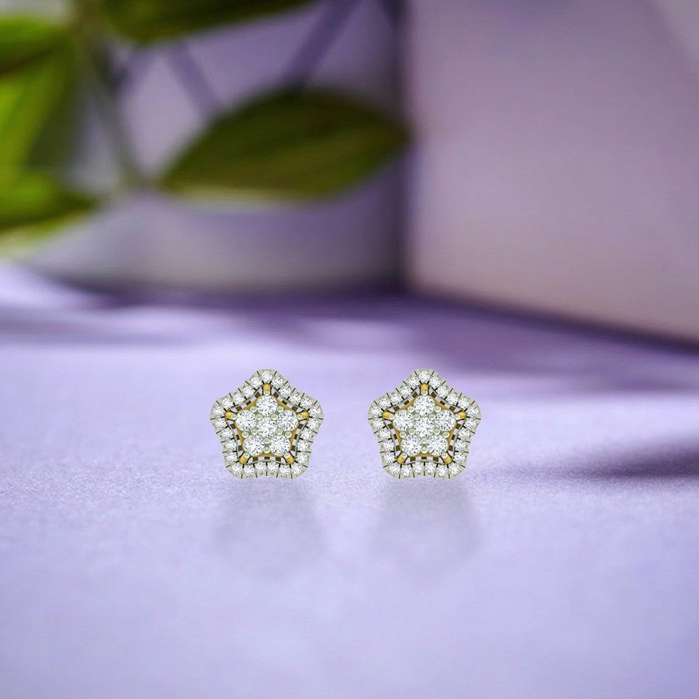 Star-shaped earrings with gold and diamond detailing on a blue surface. 