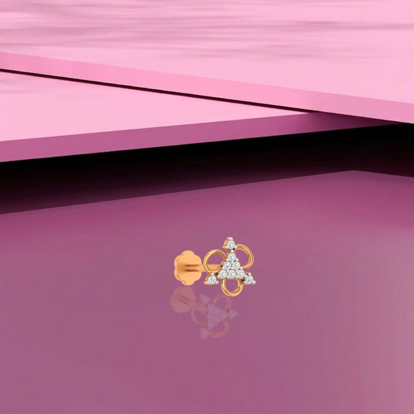 Yelow Gold and diamond stud nose pin with a triangular design on a pink surface