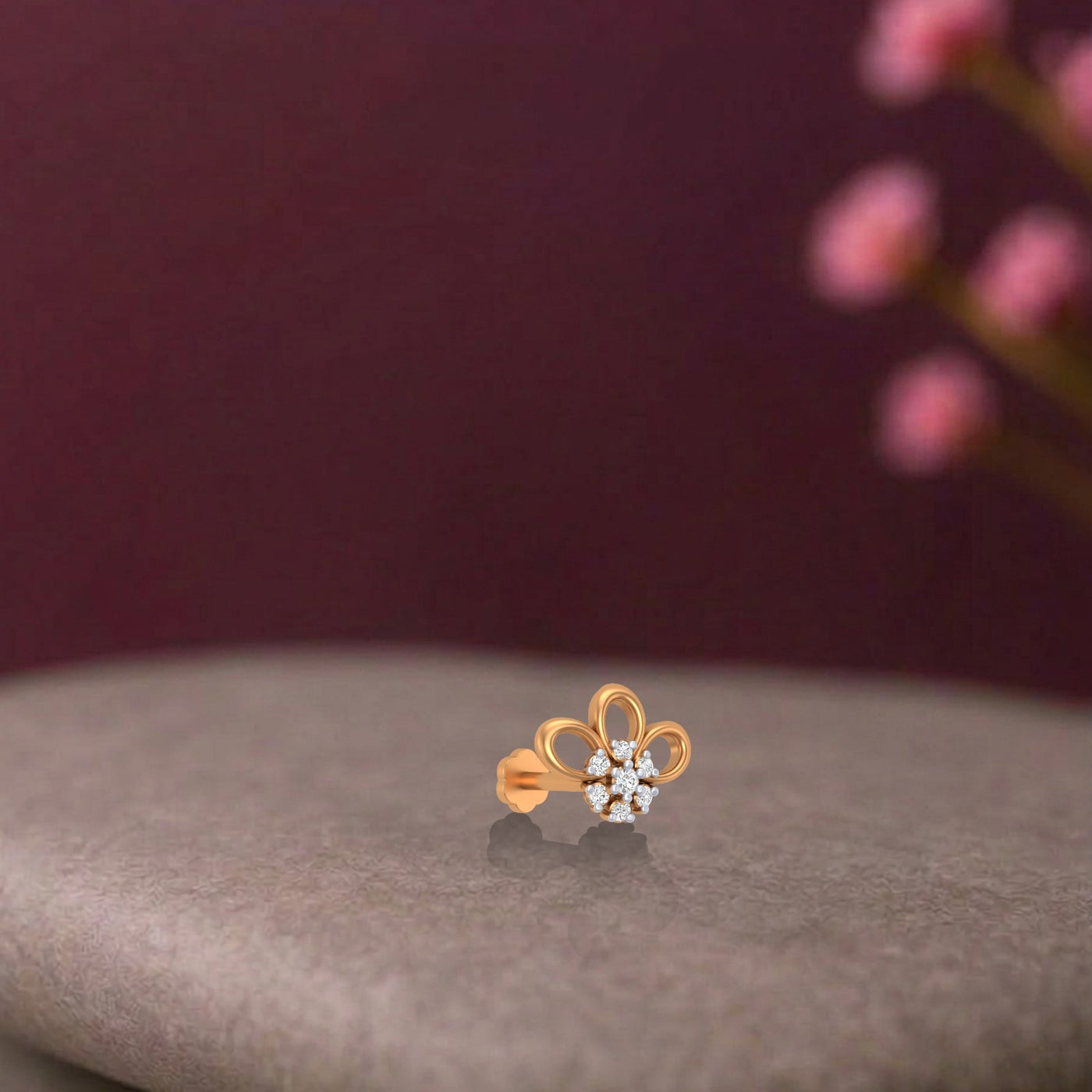 Yellow Gold and diamond stud nose pin on a stone surface with a blurred background