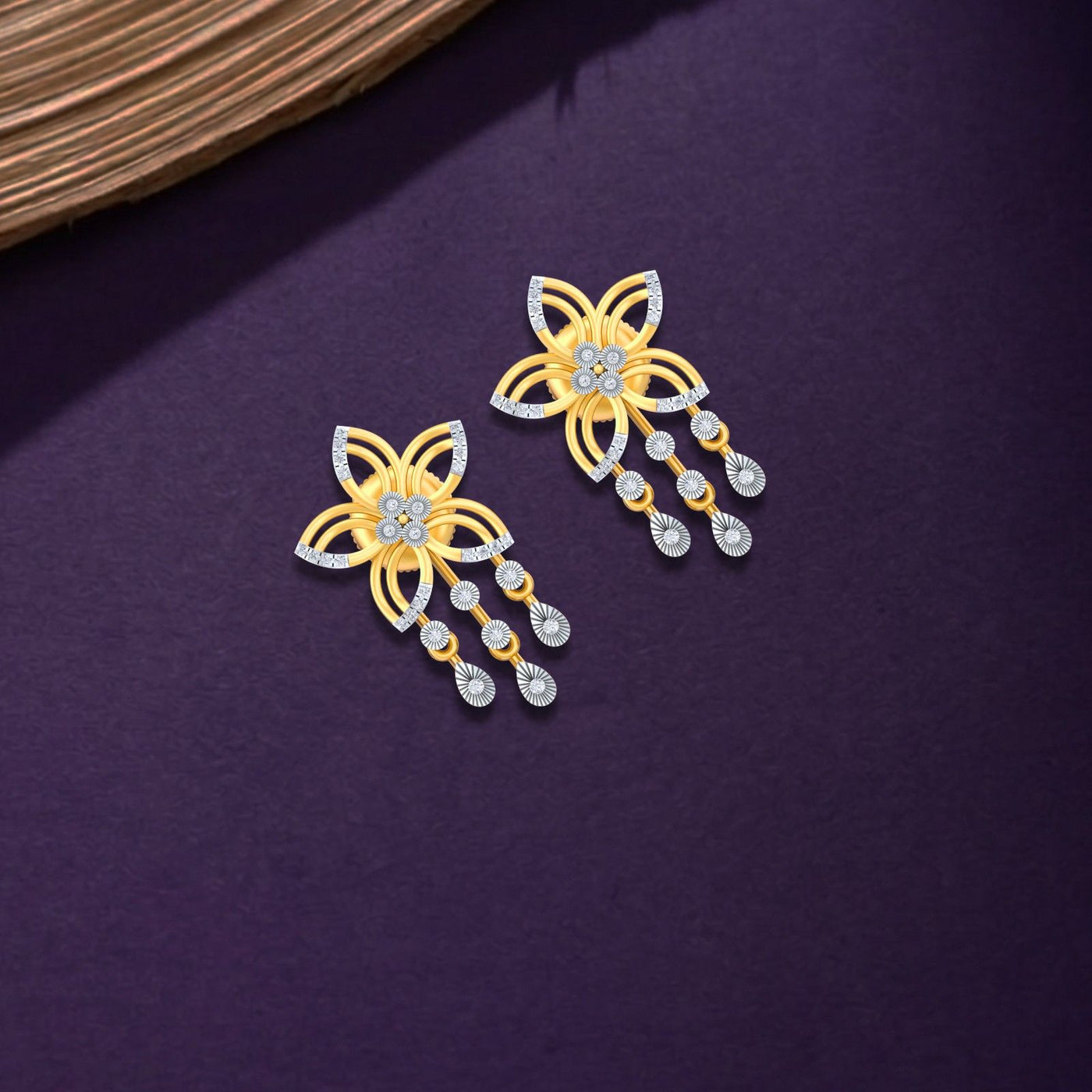 Pair of yellow gold and diamond earrings with floral design on a purple background.