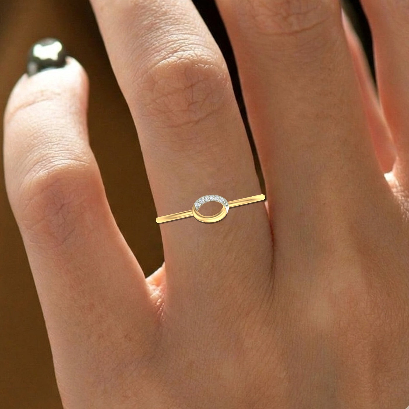 Gold ring with a small diamond on a person's finger against a blurred background