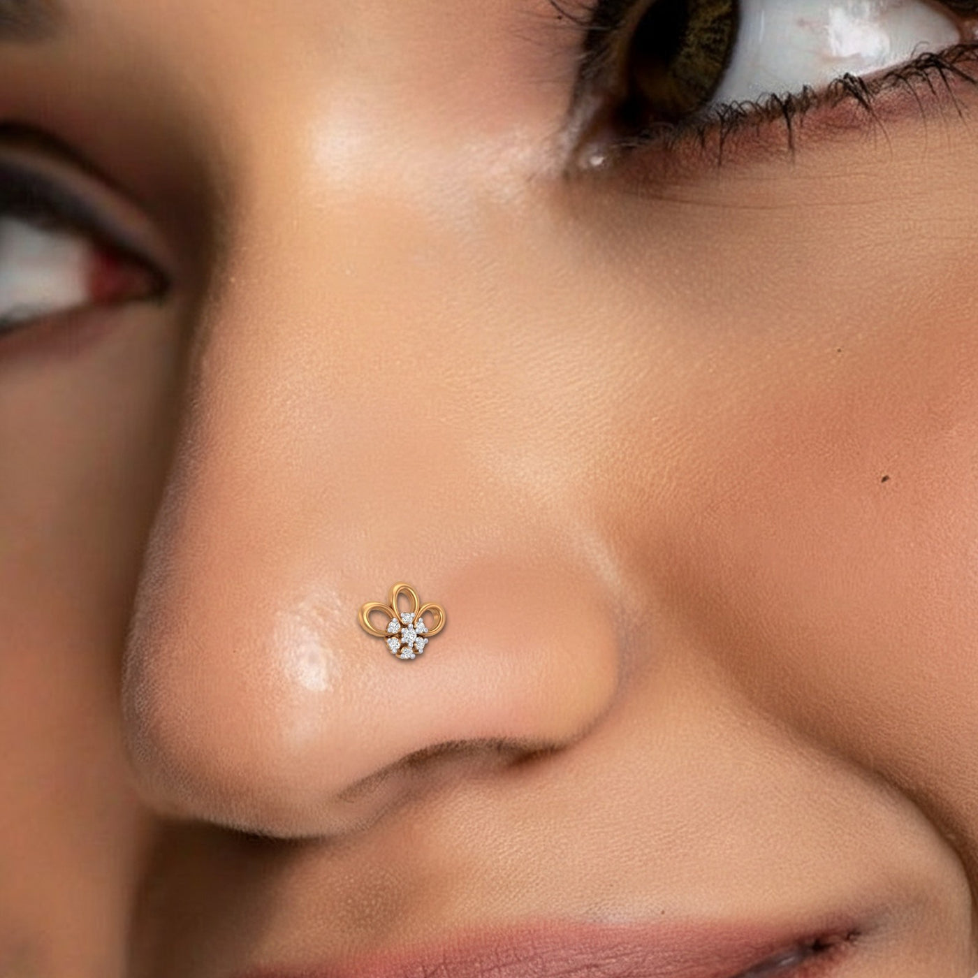 Close-up of a person wearing a gold nose ring with a floral design.