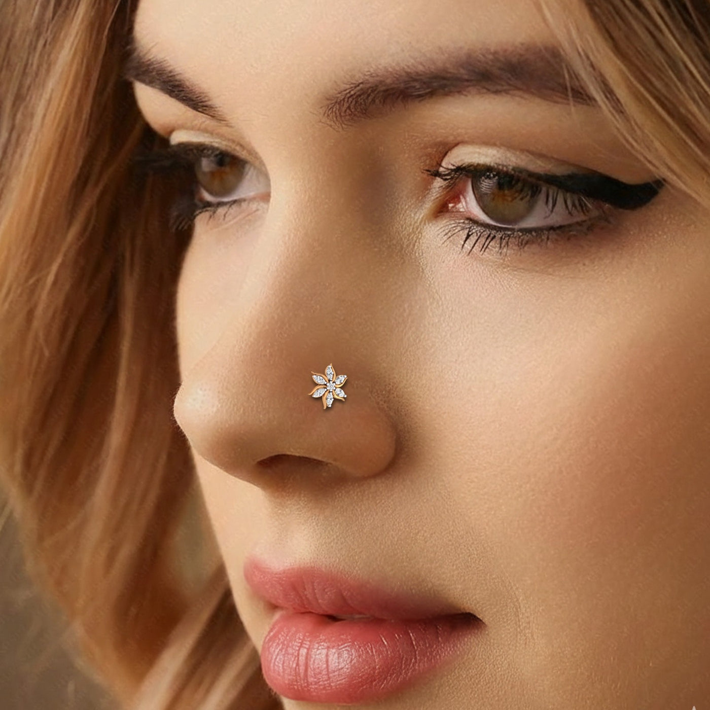 Close-up of a woman's face with a gold and diamond nose ring featuring a star-shaped design.