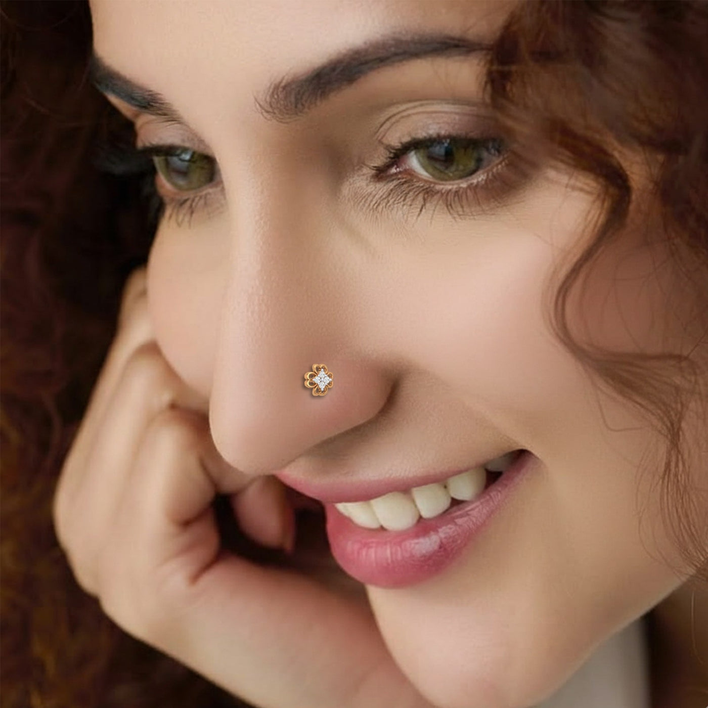 Close-up of a woman wearing a nose ring with a diamond, smiling.