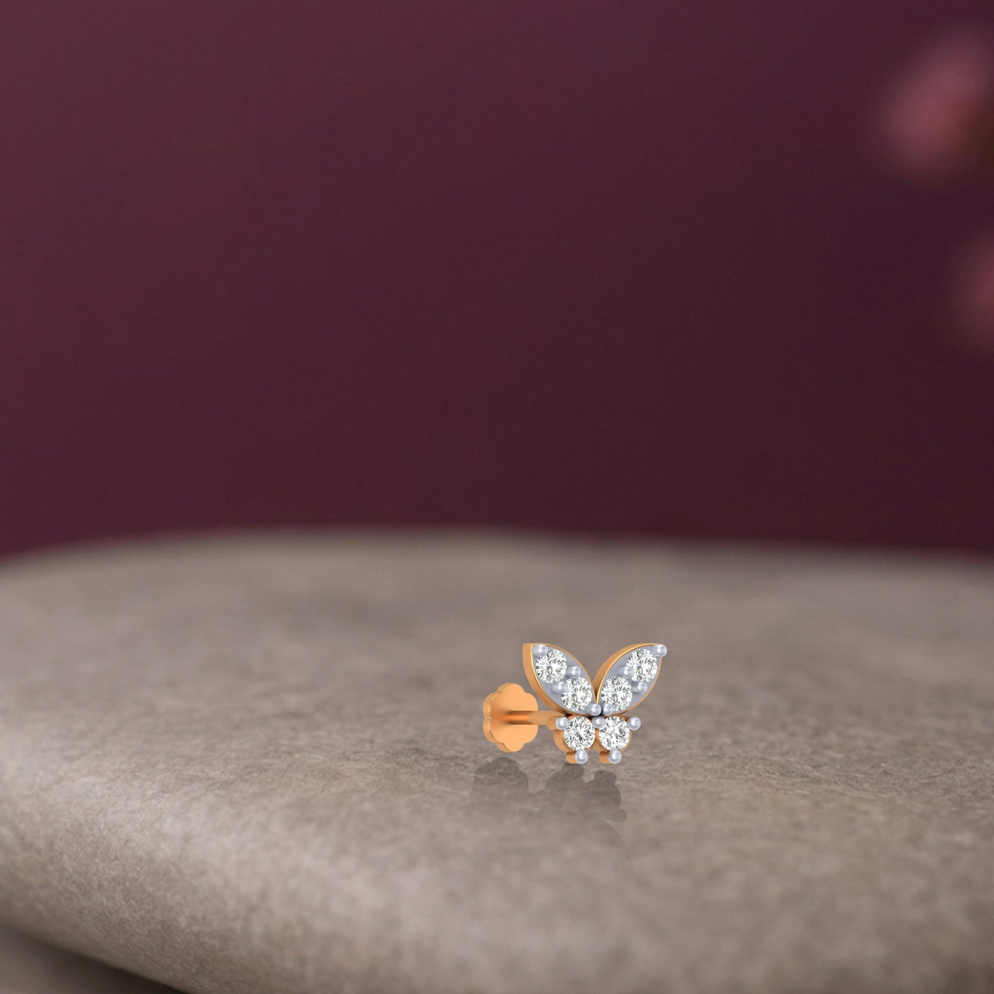 Butterfly-shaped Yellow gold and  diamond stud nosre pin accents on a neutral background