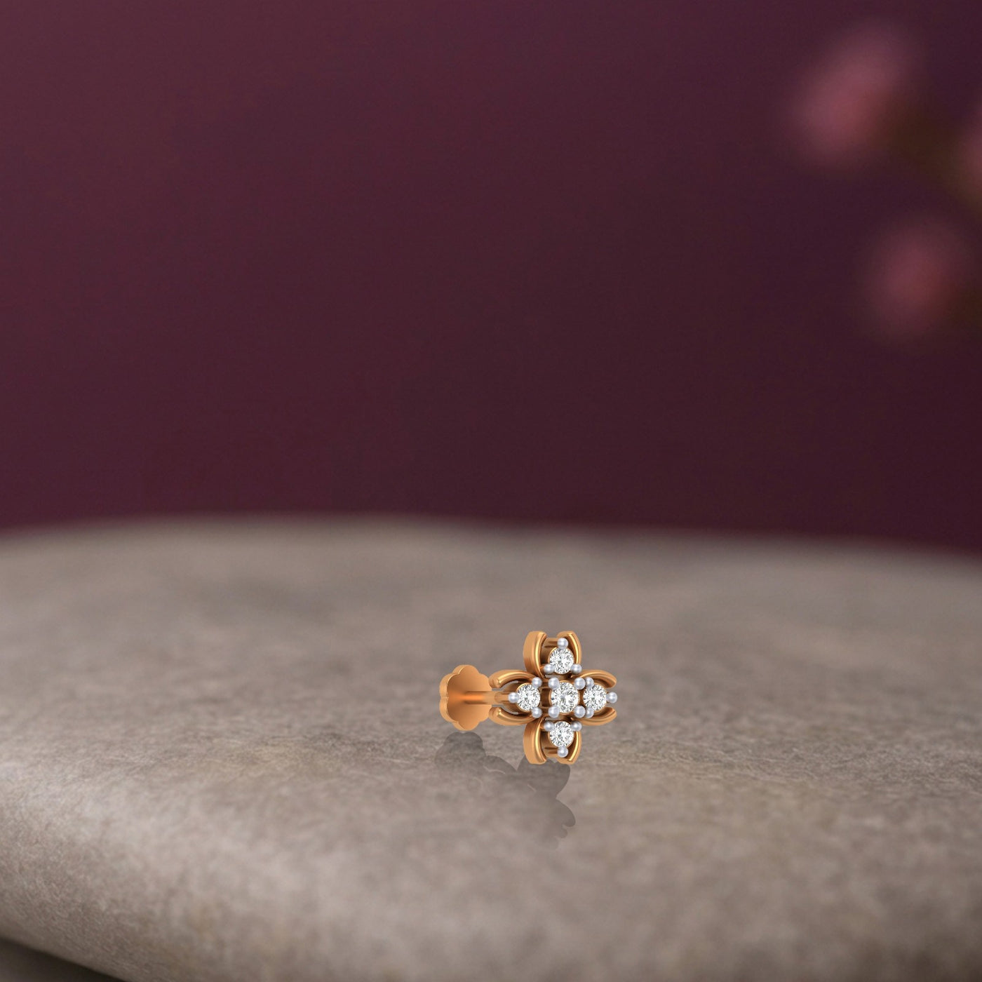 Yellow Gold and diamond stud nose pin on a textured surface