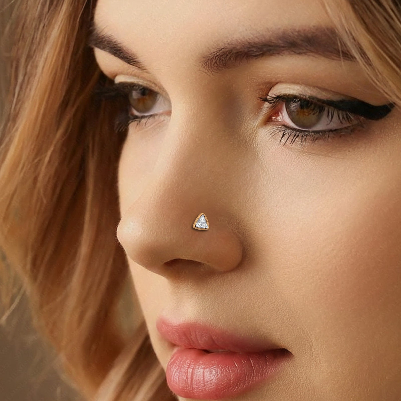 Close-up of a woman's face with a nose pin and blonde hair.