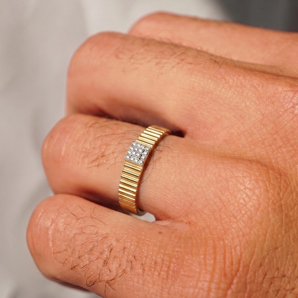 Gold ring with diamond accents on a person's finger against a neutral background