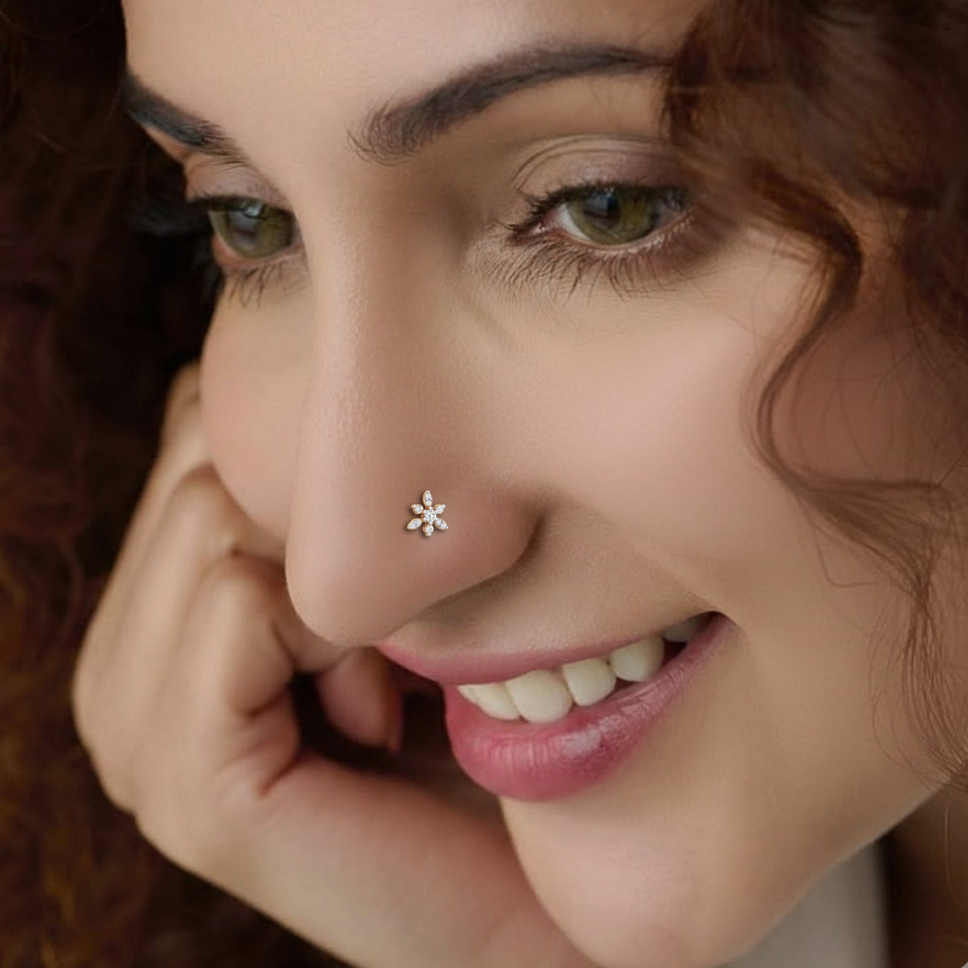 Close-up of a woman's face with a nose pin, smiling.