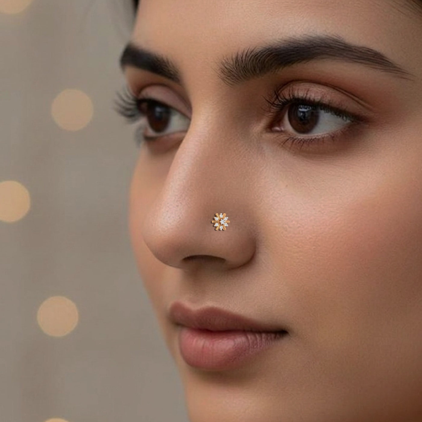 Close-up of a woman's face with a gold nose pin against a neutral background