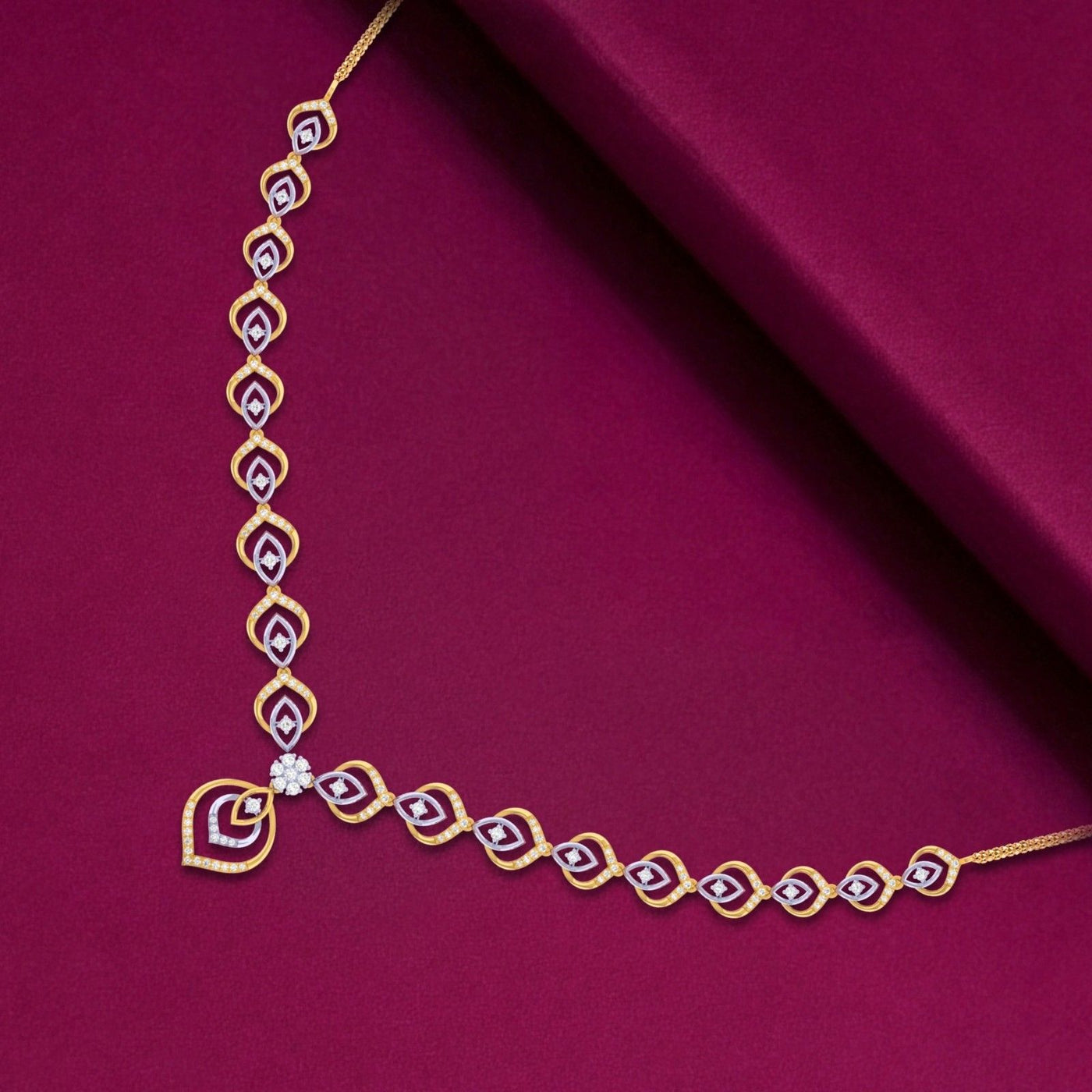 A gold and diamond necklace with teardrop-shaped on a deep magenta fabric background.