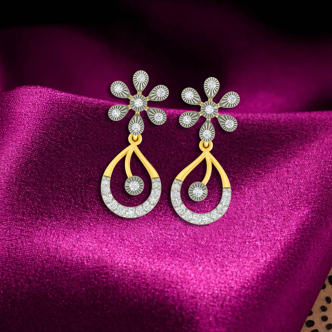 Gold and diamond floral drop earrings on a magenta fabric background.