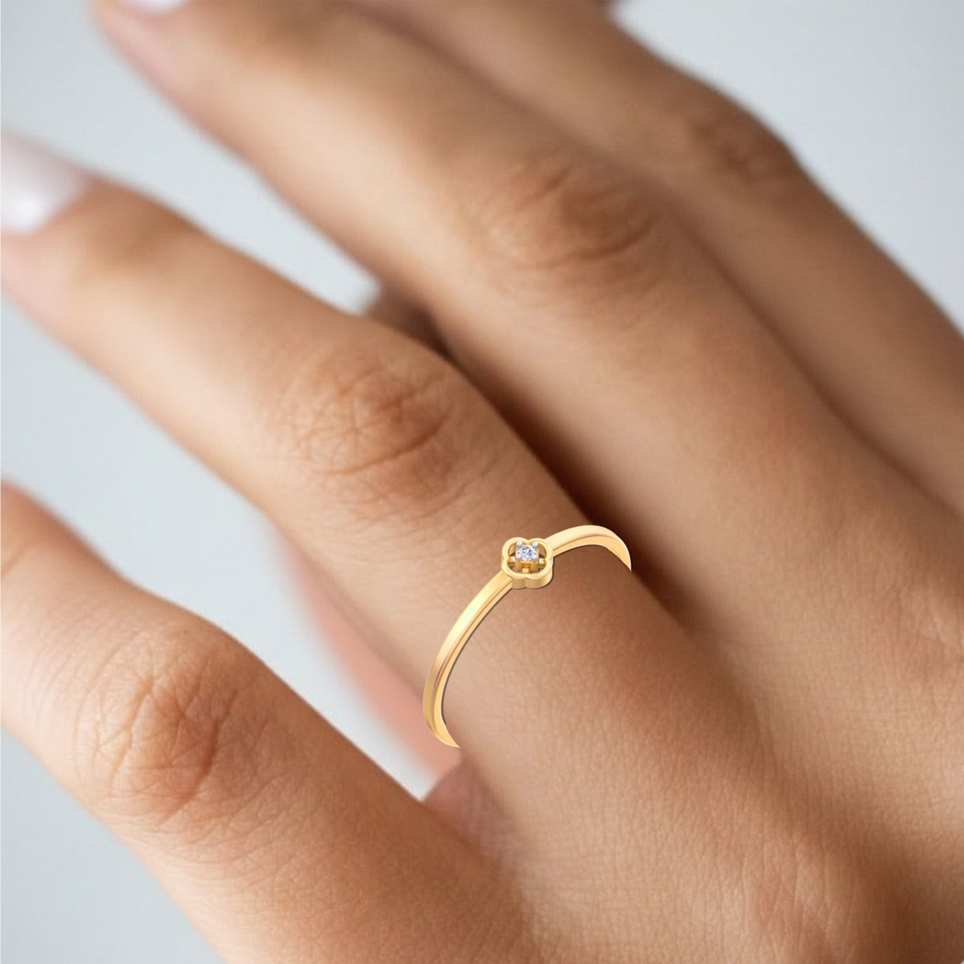 Gold ring with a small diamond on a finger against a light background
