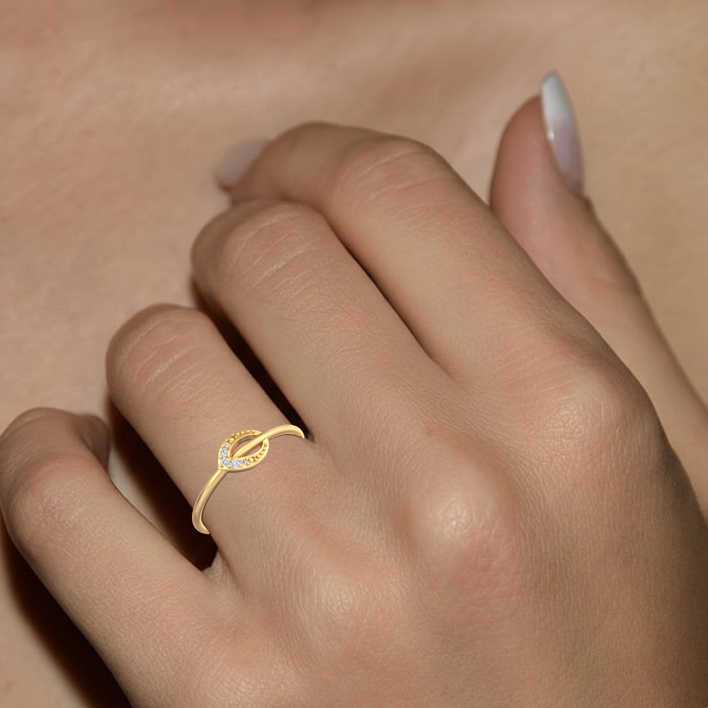 Gold ring with a decorative design on a hand against a neutral background