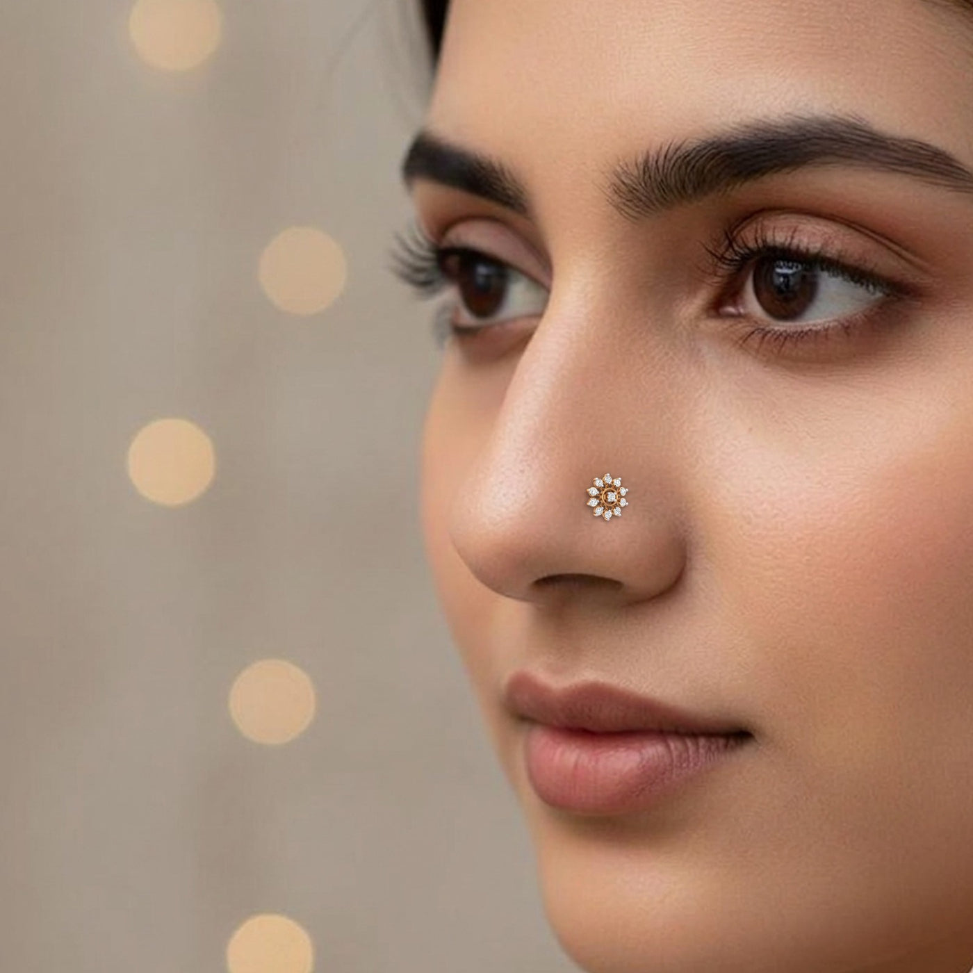 Close-up of a woman's face with a nose pin against a beige background with circular patterns.