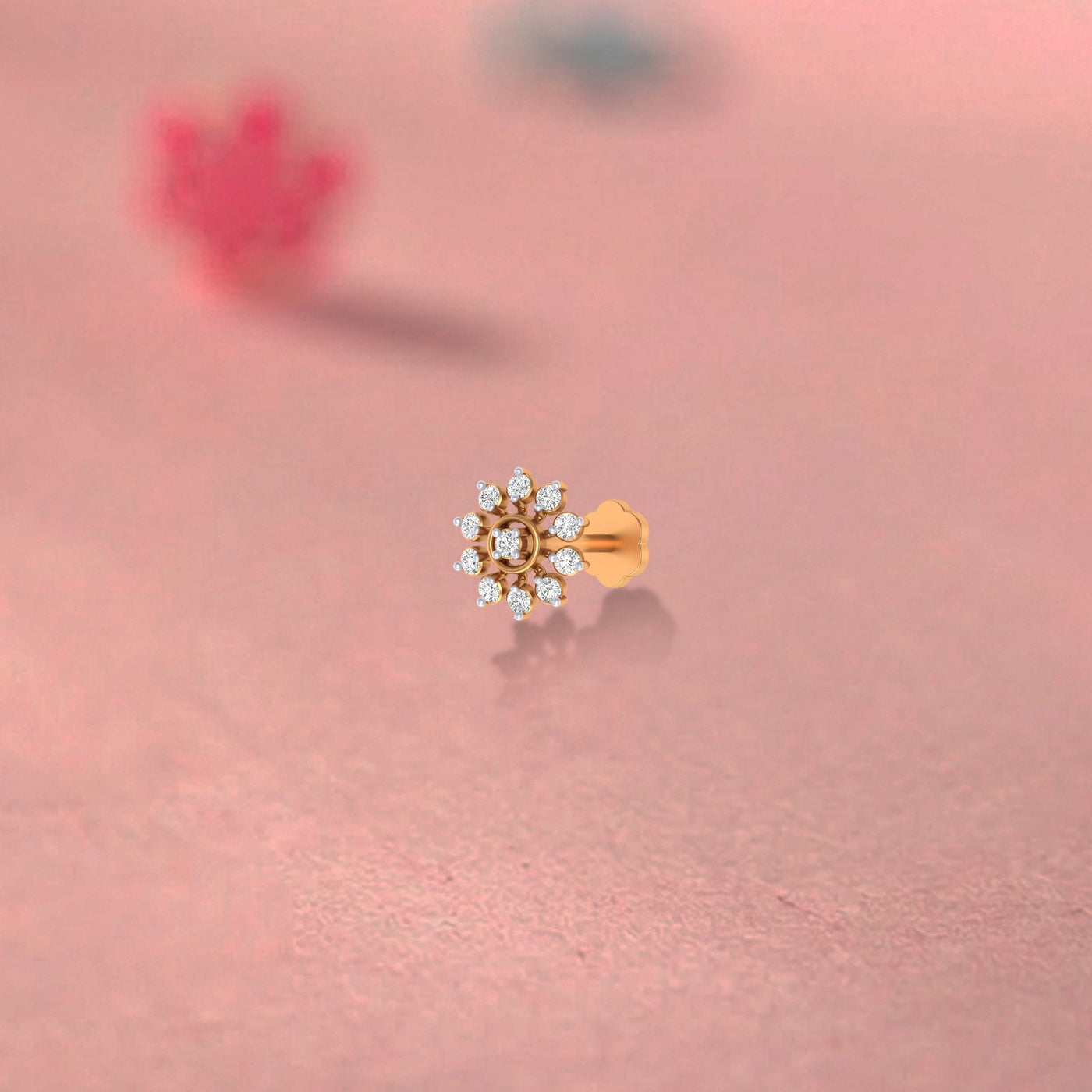 yellow gold and diamond stud nose pin with clear gemstones on a pink background