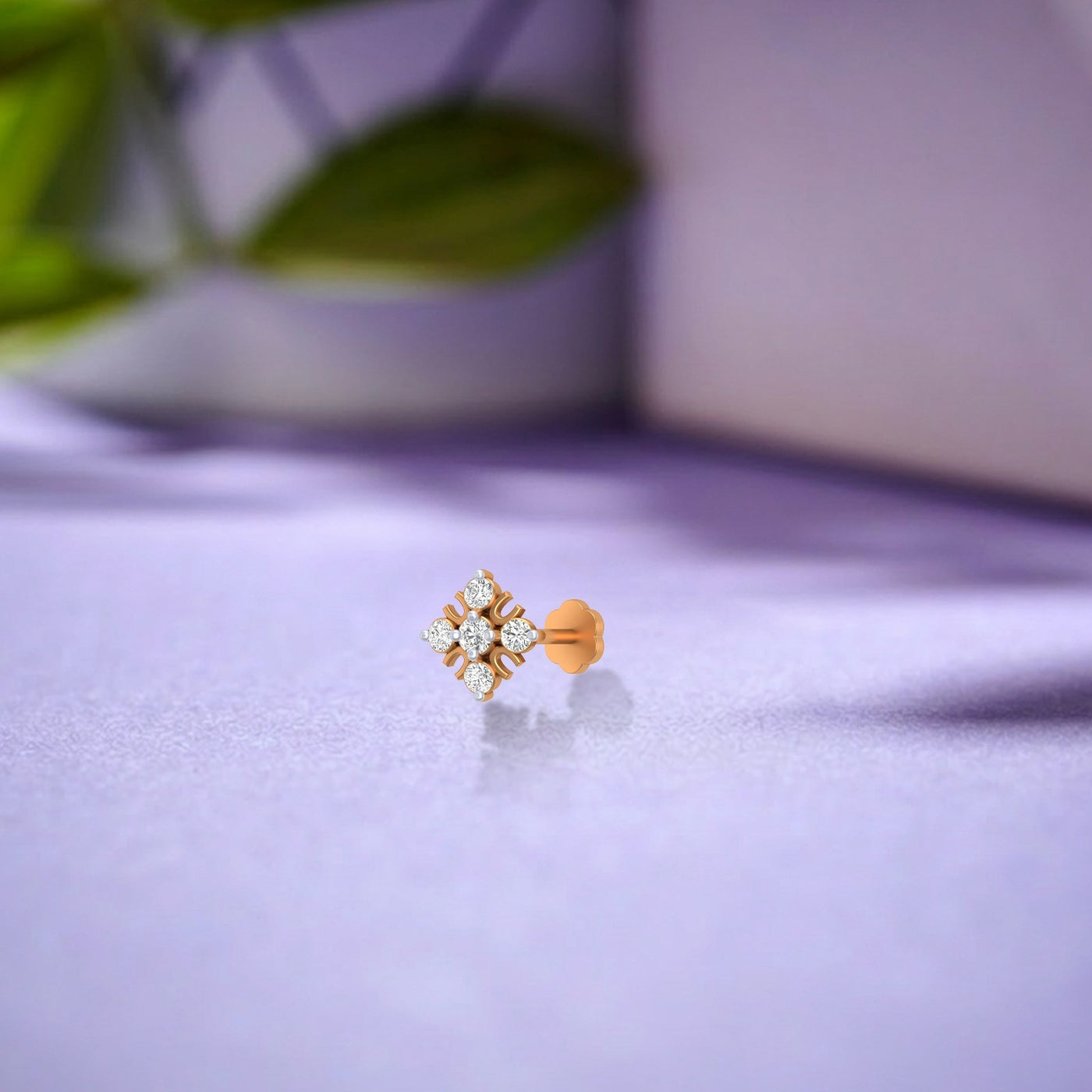 yellow gold and diamond stud nose pin on a light purple surface