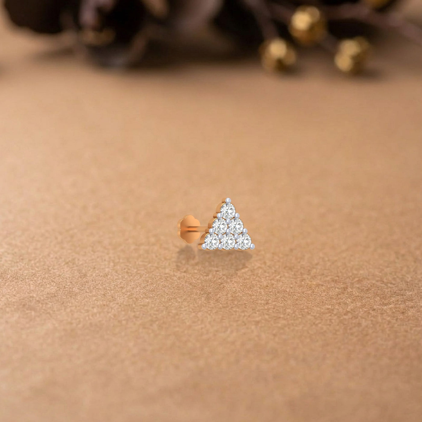 yellow gold and diamond stud nose pin on a beige surface