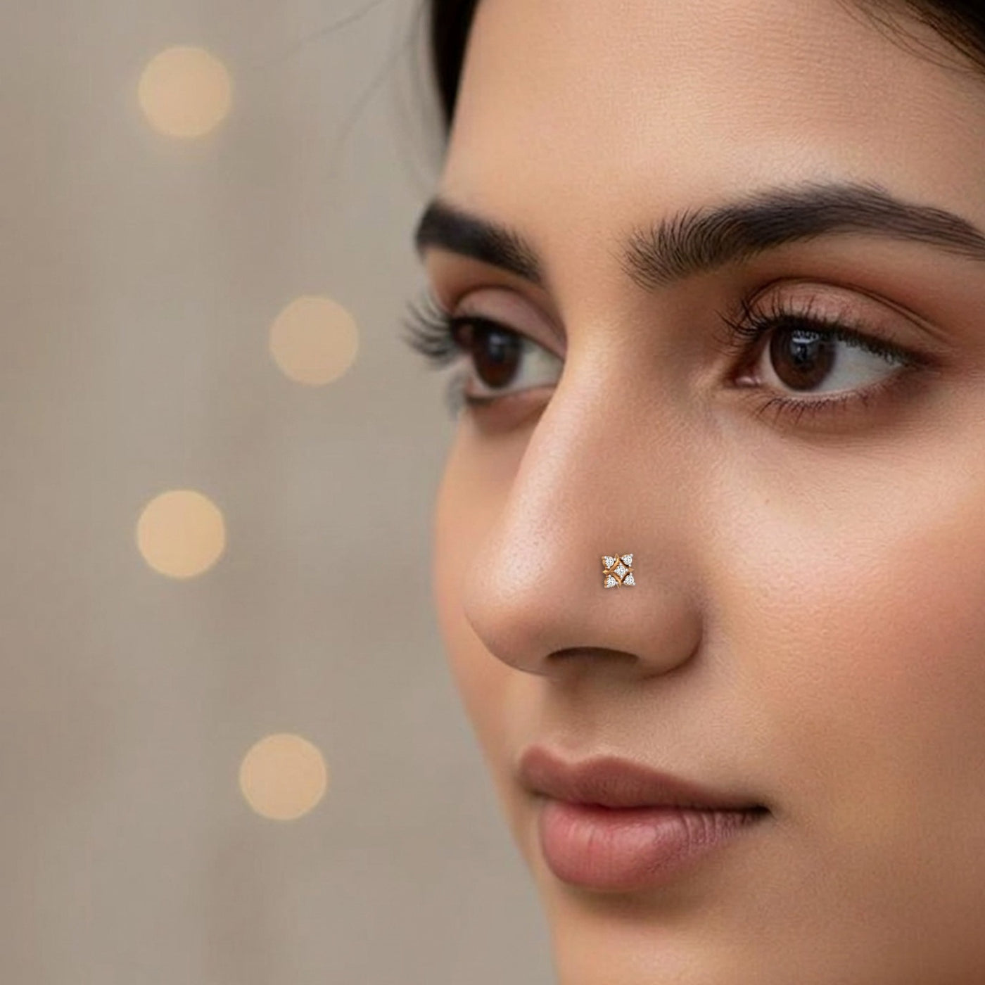 Close-up of a woman's face with a nose pin against a neutral background
