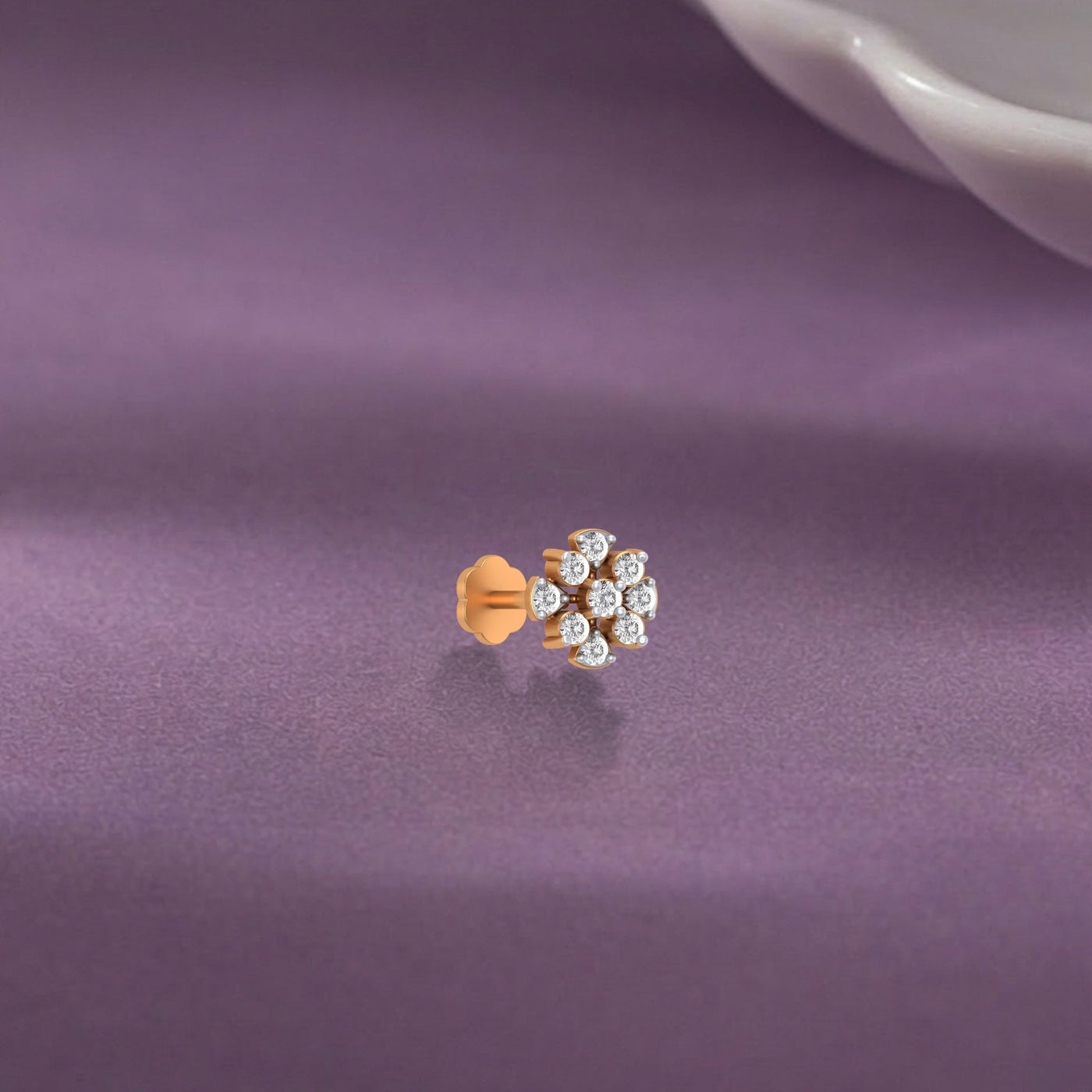 yellow gold and diamond stud nose pin with small diamonds on a purple fabric background