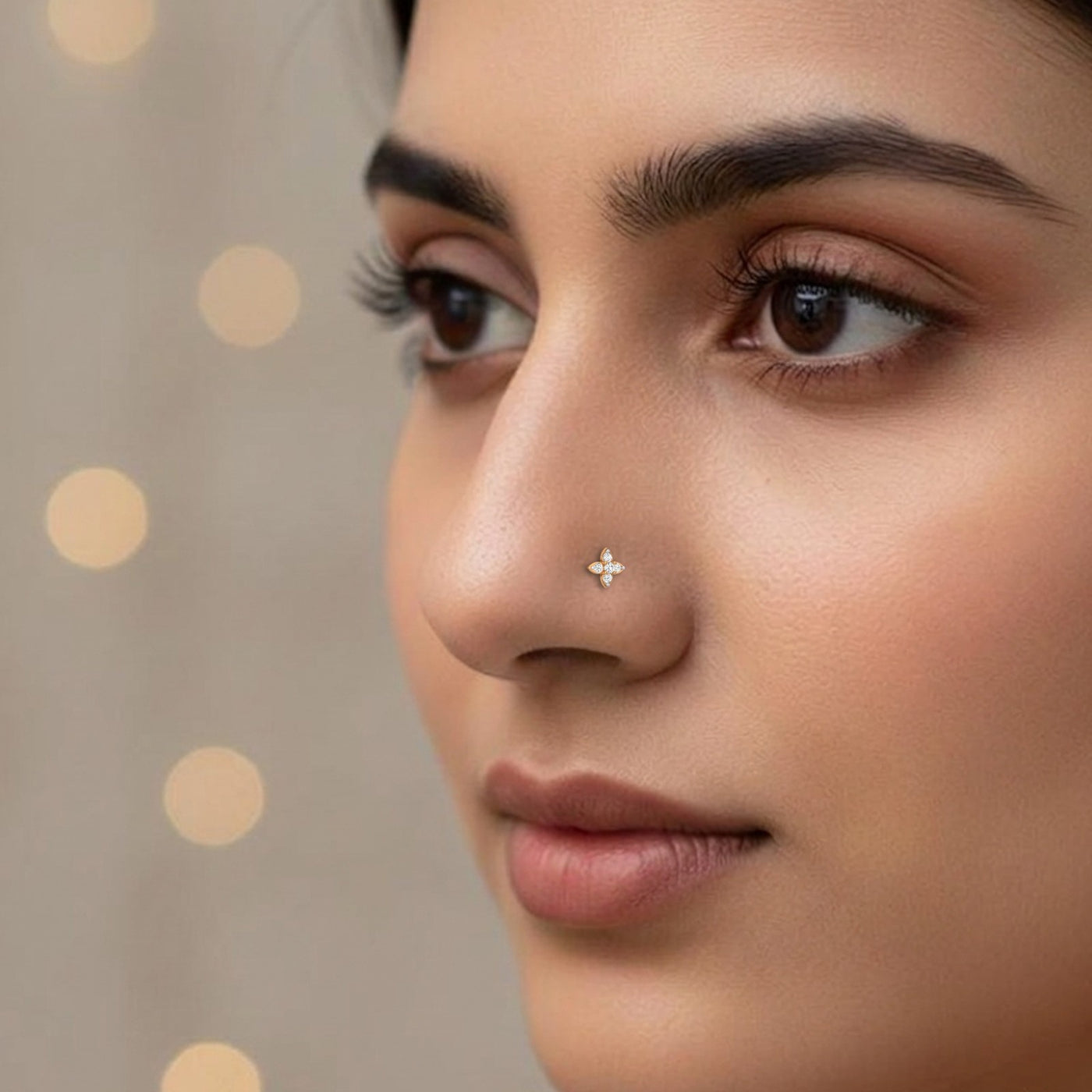 Close-up of a woman's face with a gold nose pin against a polka dot background