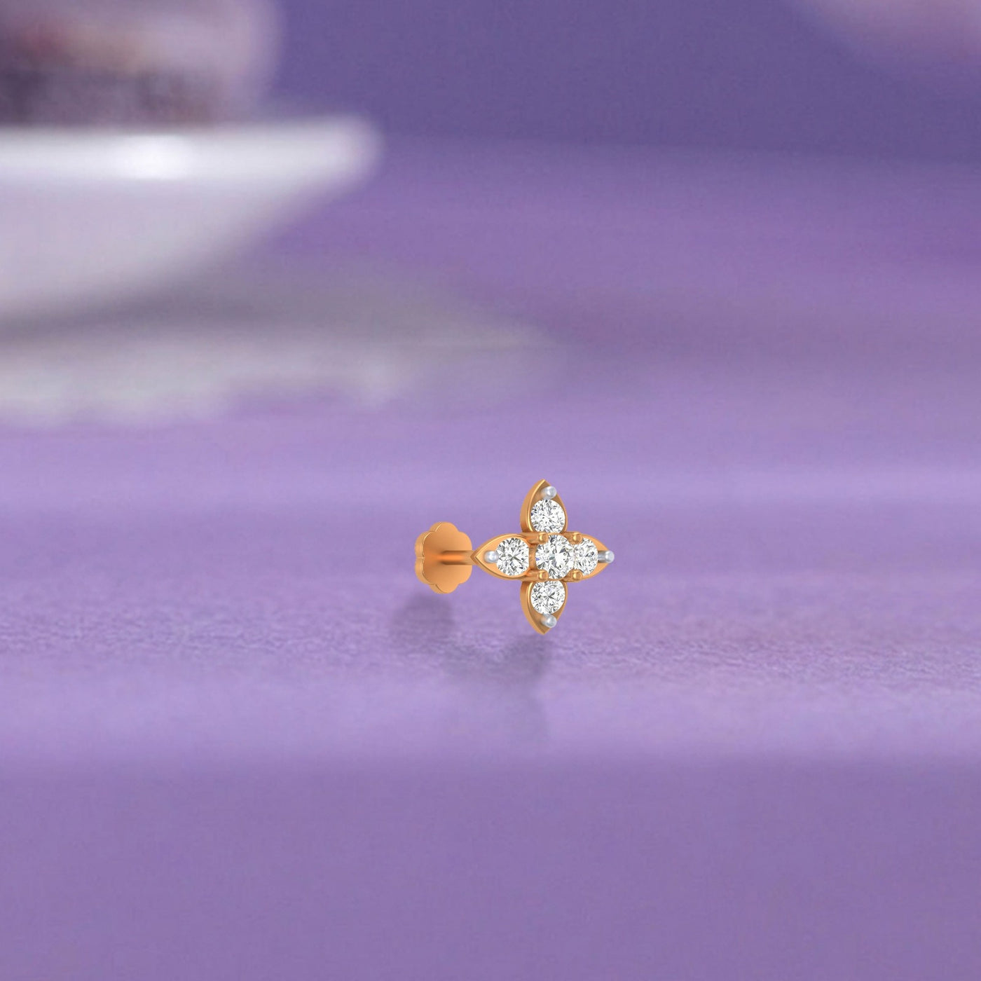 yellow gold and diamond stud nose pin with diamonds on a purple surface