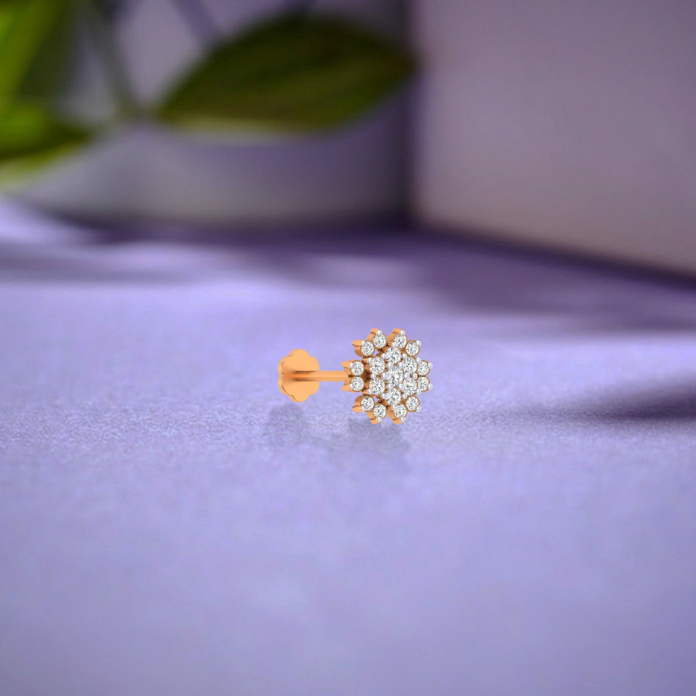 yellow gold and diamond stud nose pin with clear stones on a purple fabric background