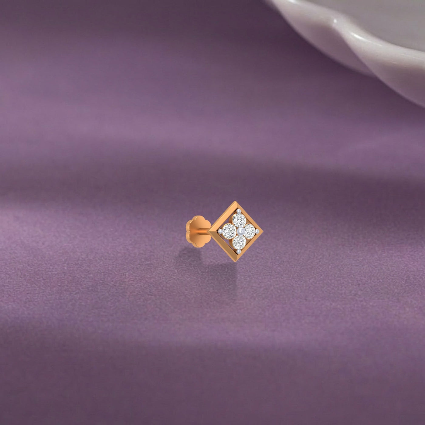 yellow gold and diamond stud nose pin with three diamonds on a purple fabric background