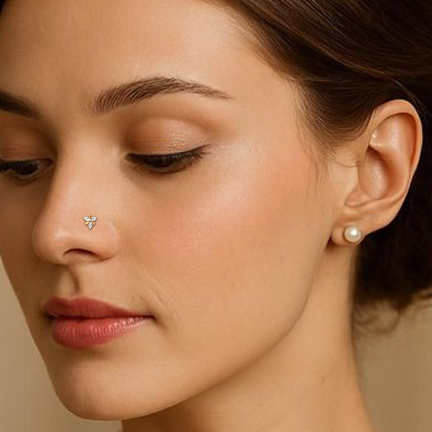Close-up of a woman's face wearing yellow gold and diamond nose ring 