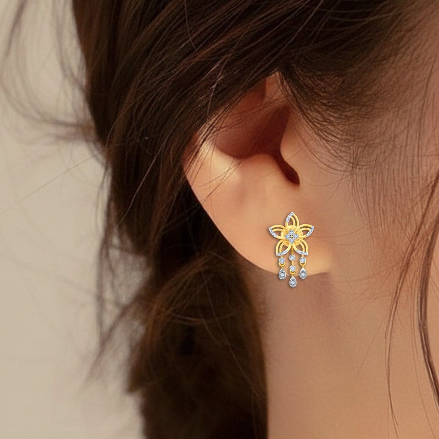 Close-up shot of a gold and diamond earrings with floral design.