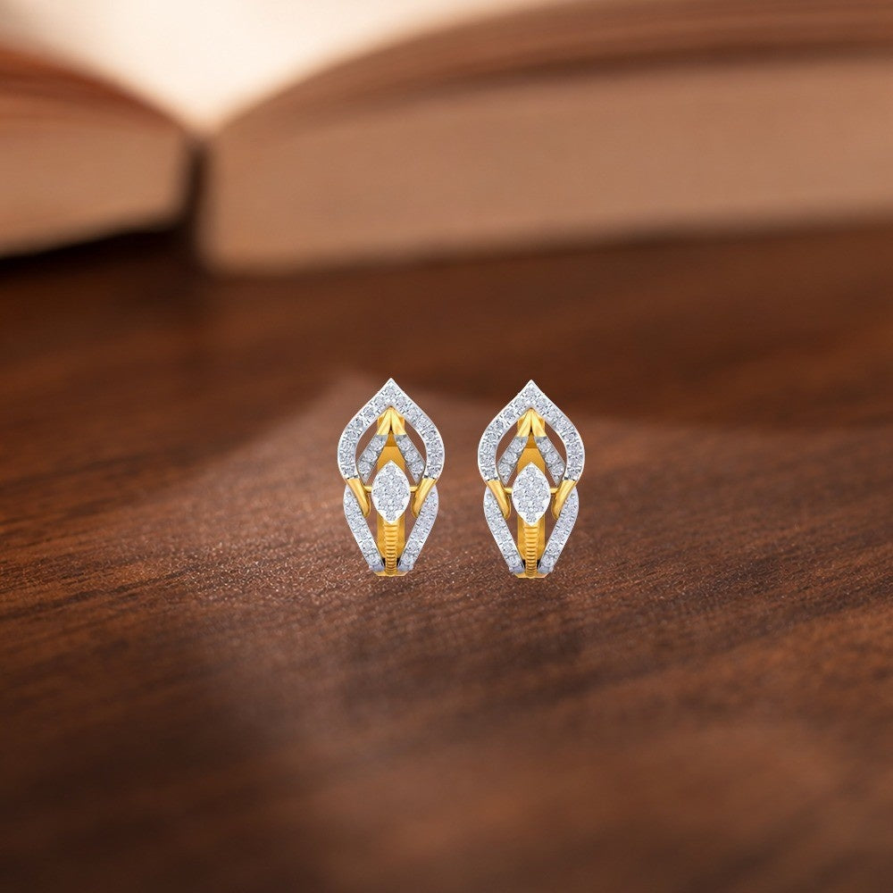 Gold earrings with diamonds, designed in a round and intricate pattern on a wooden surface.