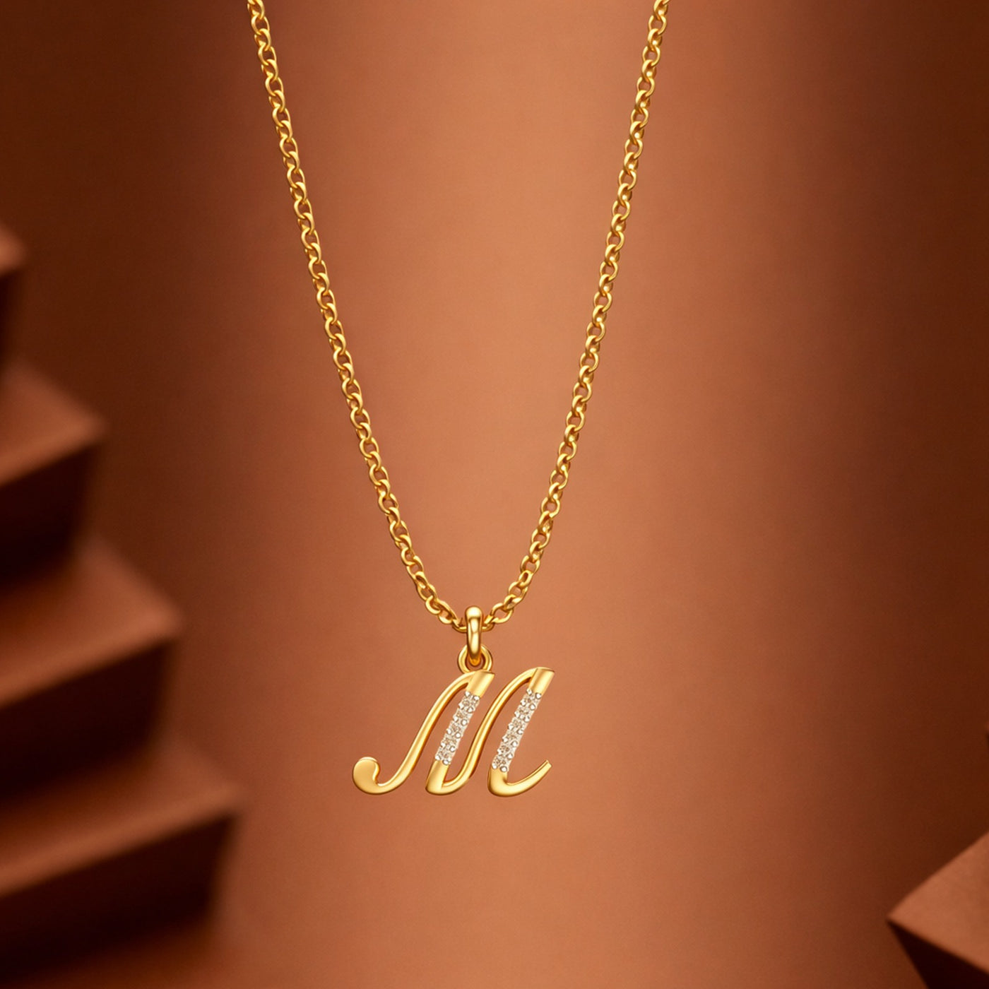 Gold necklace with a 'M' pendant on a brown background