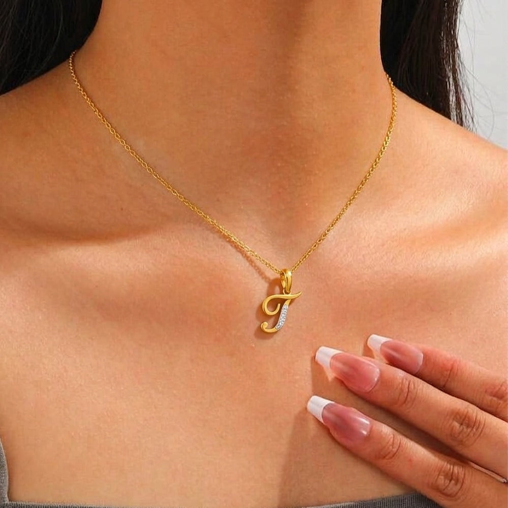 Gold necklace with a letter 'T' pendant worn by a person