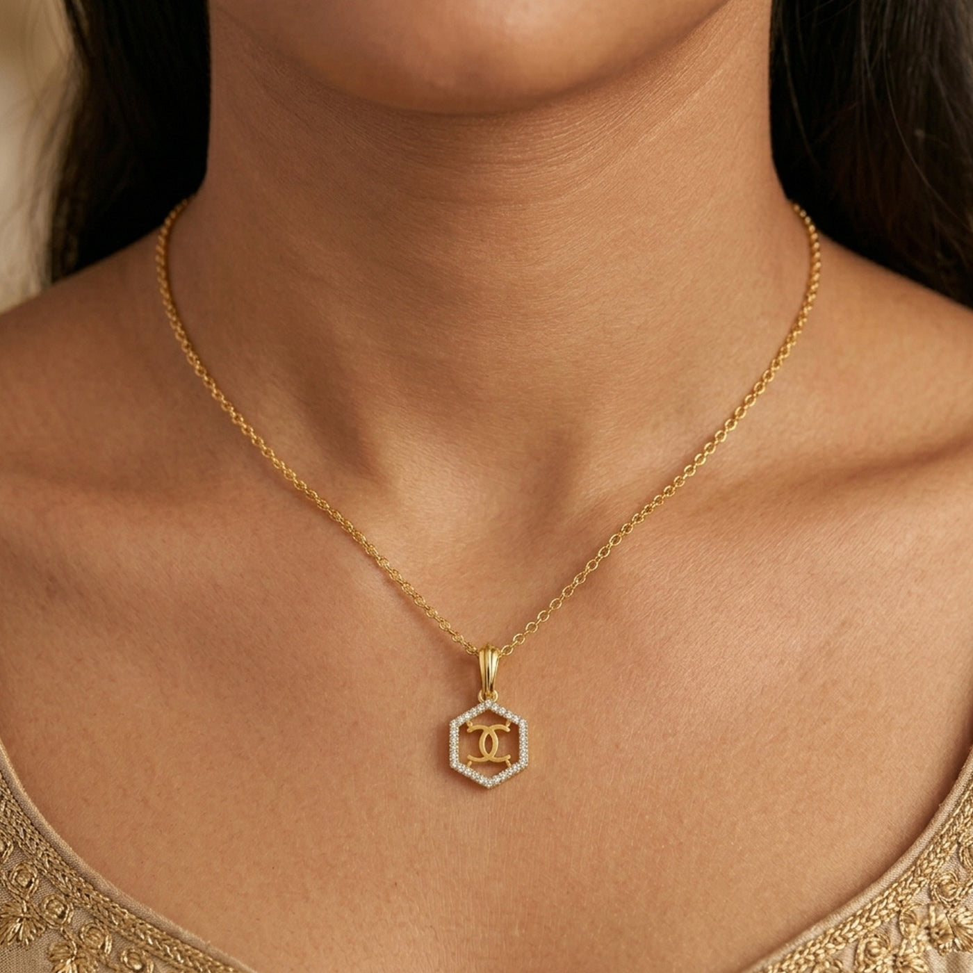 Gold and diamond pendant on a person wearing a gold top.
