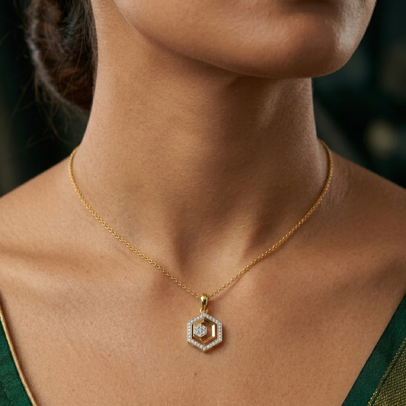 Gold pendent with a diamond pendant on a person wearing a green dress.