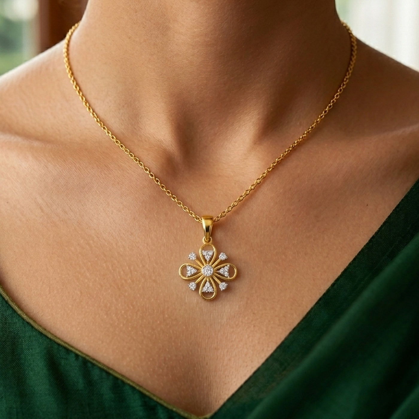 Gold necklace with a diamond pendant worn by a person in a green dress.